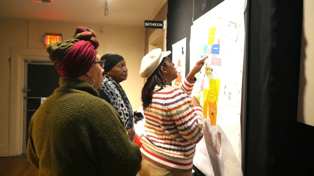 Three Opelousas Museum visitors looking at map hanging on the wall. One visitor points on the map.
