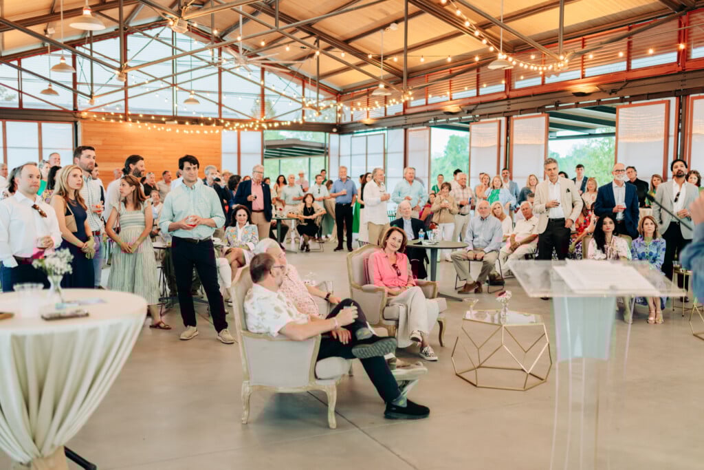 Inside Moncus Park Doerle Farmers Market Pavilion with people gathered, sitting and standing