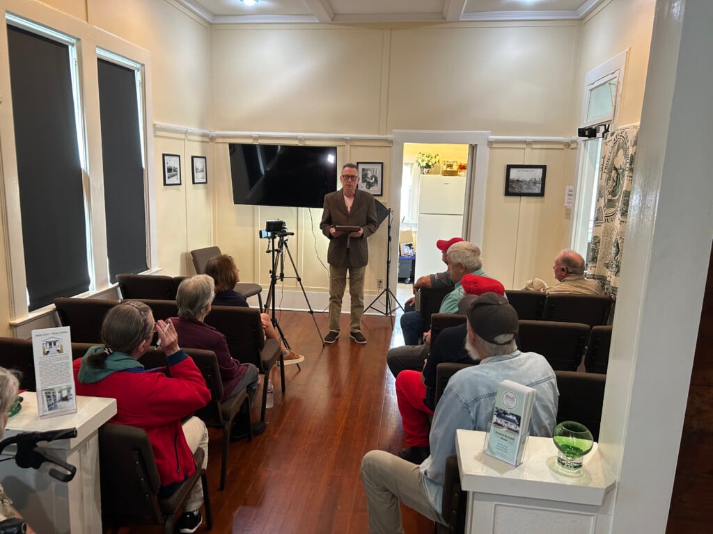 Notre Propre Histoire project at Bernard Bertrand house in Rayne. People sitting in side rows with project manager Brian standing in the front next to recording equipment.