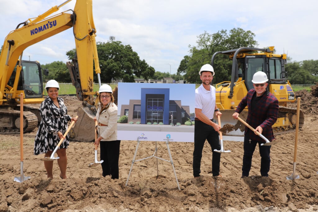 OnPath Credit Union Lafayette groundbreaking ceremony. People posing at construction site with hard hats on. Machinery is behind them and a rendering of the building.