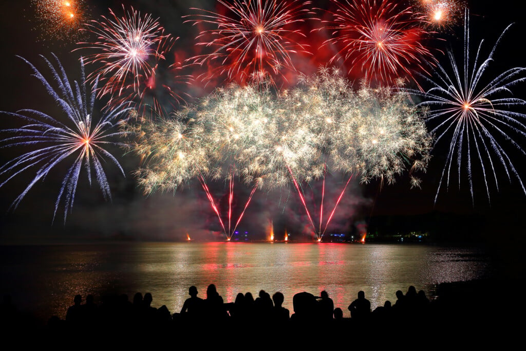 July 4th Events in Acadiana: Beautiful Large Colorful Fireworks Display With Unrecognizable Crowd People Watching
