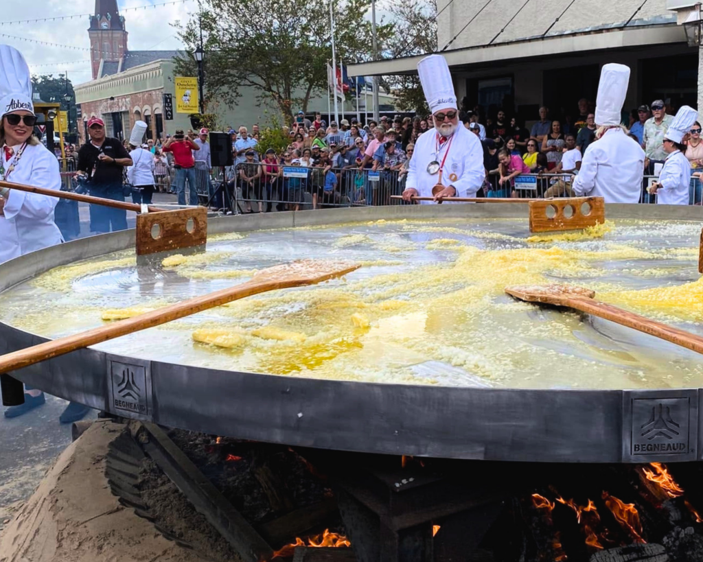 Abbeville's Giant Omelette Festival: November Festivals in Acadiana. People in chef hats using large tools to stir eggs