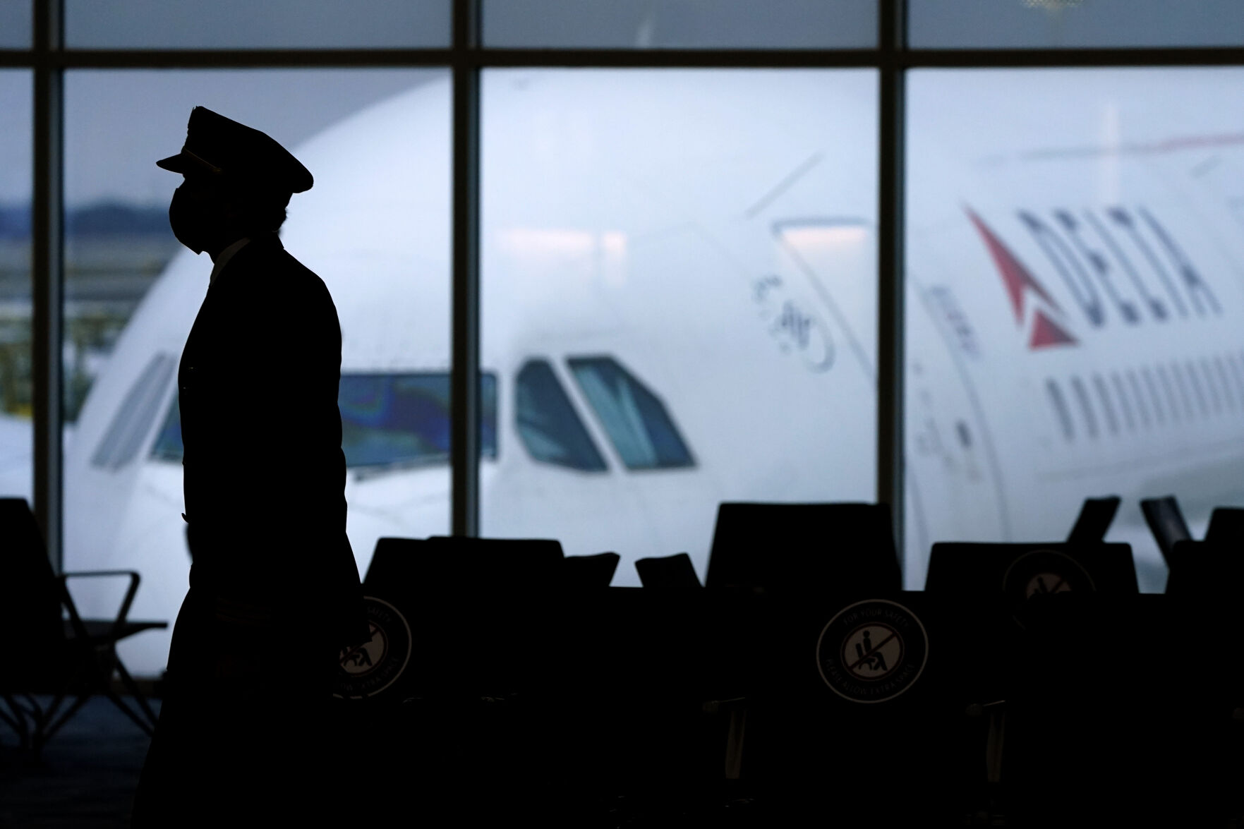 <p>FILE - In this Thursday, Feb. 18, 2021, file photo, a Delta Airlines pilot wears a face mask as he walks through a terminal at Hartsfield-Jackson International Airport in Atlanta. On Friday, Oct. 15, The Associated Press reported on stories circulating online incorrectly claiming a Delta Airlines pilot who had recently been vaccinated for COVID-19 died mid-flight within the last 10 days, forcing the plane to make an emergency landing. (AP Photo/Charlie Riedel, File)</p>