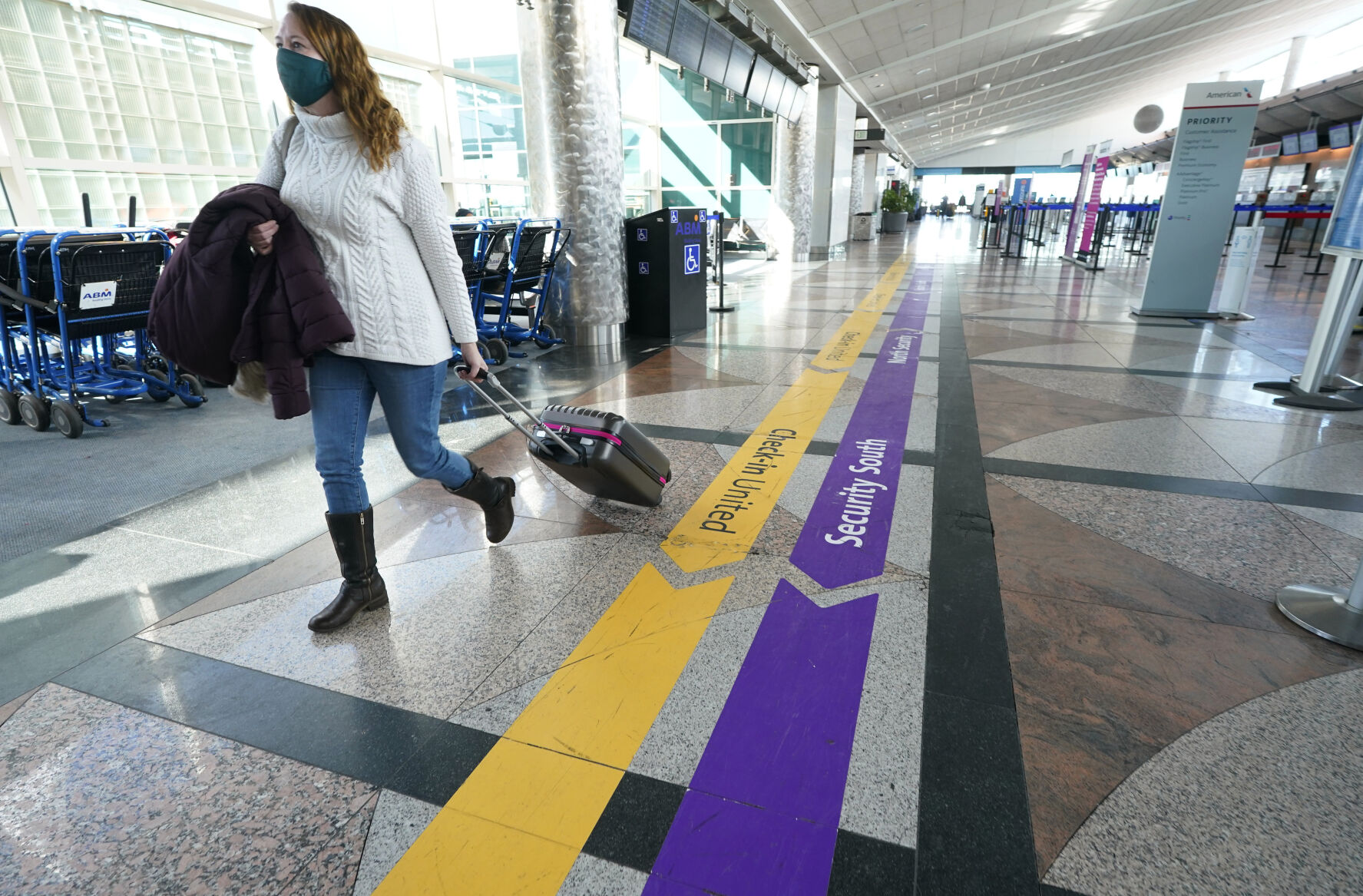 <p>FILE - In this Feb. 18, 2021, file photo, a traveler wears a face covering while hurrying through a near-empty check-in counter area in the main terminal of Denver International Airport in Denver. On Friday, Oct. 15, The Associated Press reported on stories circulating online incorrectly claiming that employees refused to show up to work at five of the airport’s restaurants because of a supposed COVID-19 vaccine mandate. (AP Photo/David Zalubowski, File)</p>