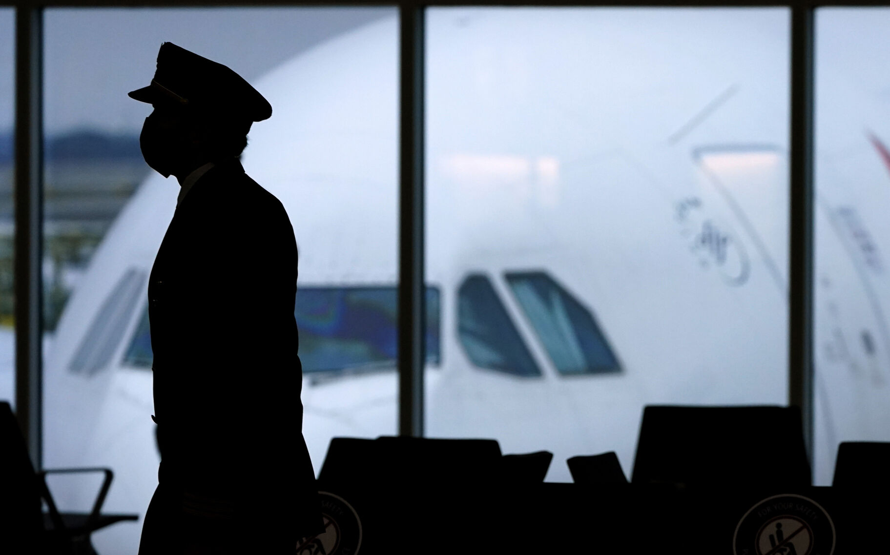 <p>FILE - In this Thursday, Feb. 18, 2021, file photo, a pilot wears a face mask to help prevent the spread of the coronavirus as he walks through a terminal at Hartsfield-Jackson International Airport in Atlanta. On Friday, Oct. 22, The Associated Press reported on stories circulating online incorrectly claiming that vaccine-related strokes in pilots have caused an “epidemic of plane crashes.” (AP Photo/Charlie Riedel, File)</p>