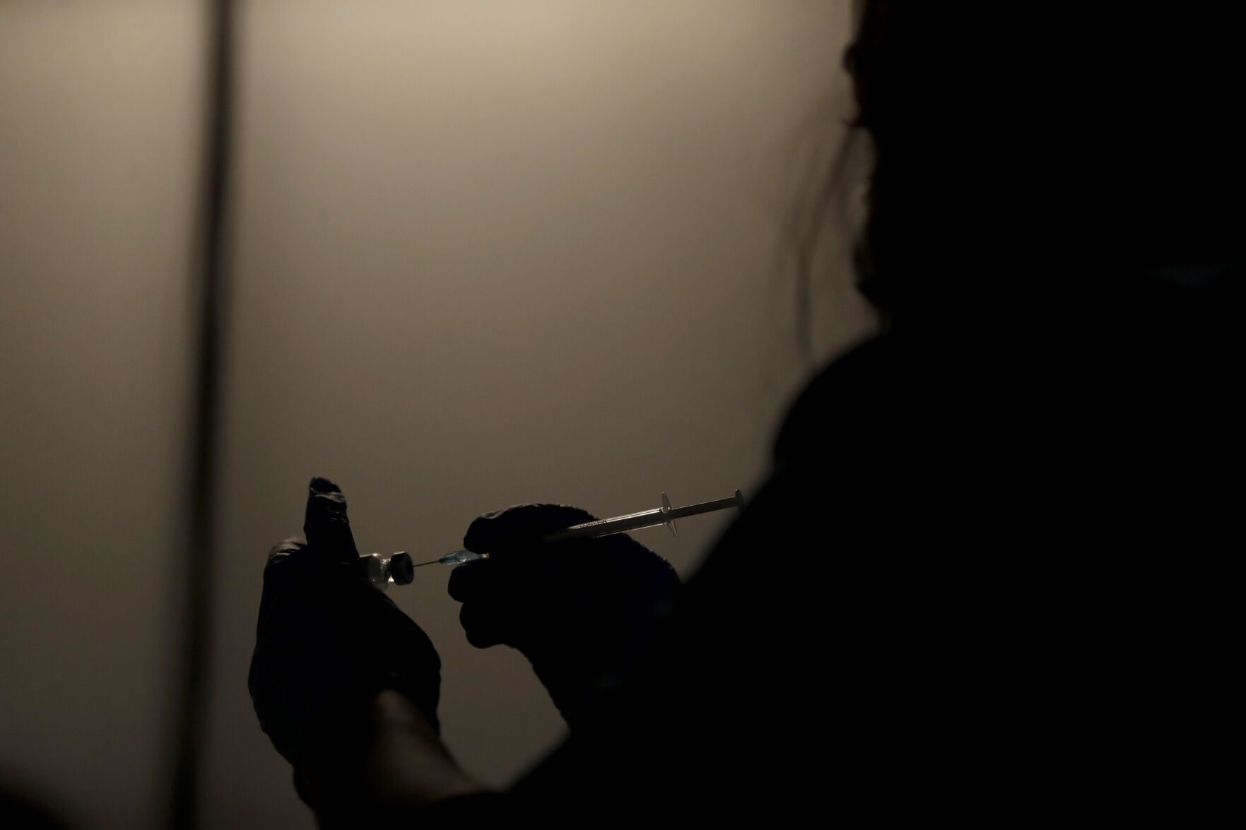<p>FILE - In this May 1, 2021, file photo, a volunteer vaccinator prepares to administer a dose of the Pfizer coronavirus vaccine at a vaccine center in Neasden, north London. On Friday, Oct. 15, The Associated Press reported on stories circulating online incorrectly claiming a video shows people dropping “dead” outside a COVID-19 vaccination clinic in London after receiving a shot. (AP Photo/Matt Dunham, File)</p>