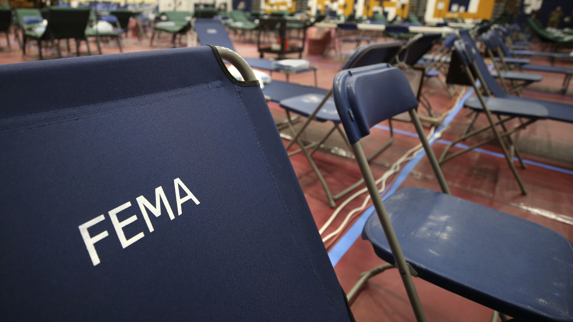 <p>FILE - In this March 24, 2020, file photo, a portable cot with the Federal Emergency Management Agency logo FEMA printed on the backrest, along with other cots, line the basketball court at a makeshift medical facility in a gymnasium at Southern New Hampshire University in Manchester, N.H. On Friday, Oct. 22, The Associated Press reported on stories circulating online incorrectly claiming FEMA workers aren’t subject to a vaccine mandate, and also falsely asserting that they’re being used to replace health care personnel who refuse to comply with such mandates. (AP Photo/Charles Krupa, File)</p>