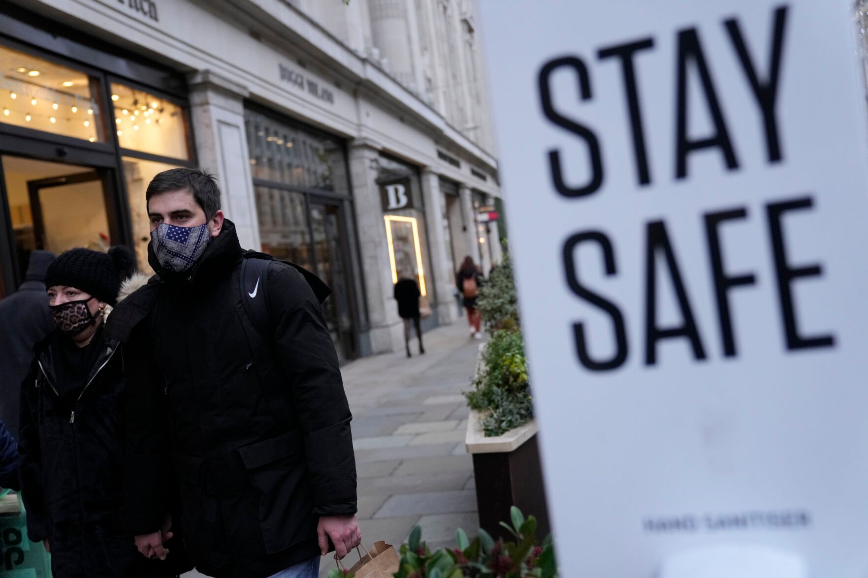 <p>FILE- Pedestrians wearing face masks against the coronavirus walk along Regent Street in London, Tuesday, Nov. 30, 2021. A pandemic-weary world faces weeks of confusing uncertainty as countries restrict travel and take other steps to halt the newest potentially risky coronavirus mutant before anyone knows just how dangerous omicron really is. (AP Photo/Alastair Grant, File)</p>