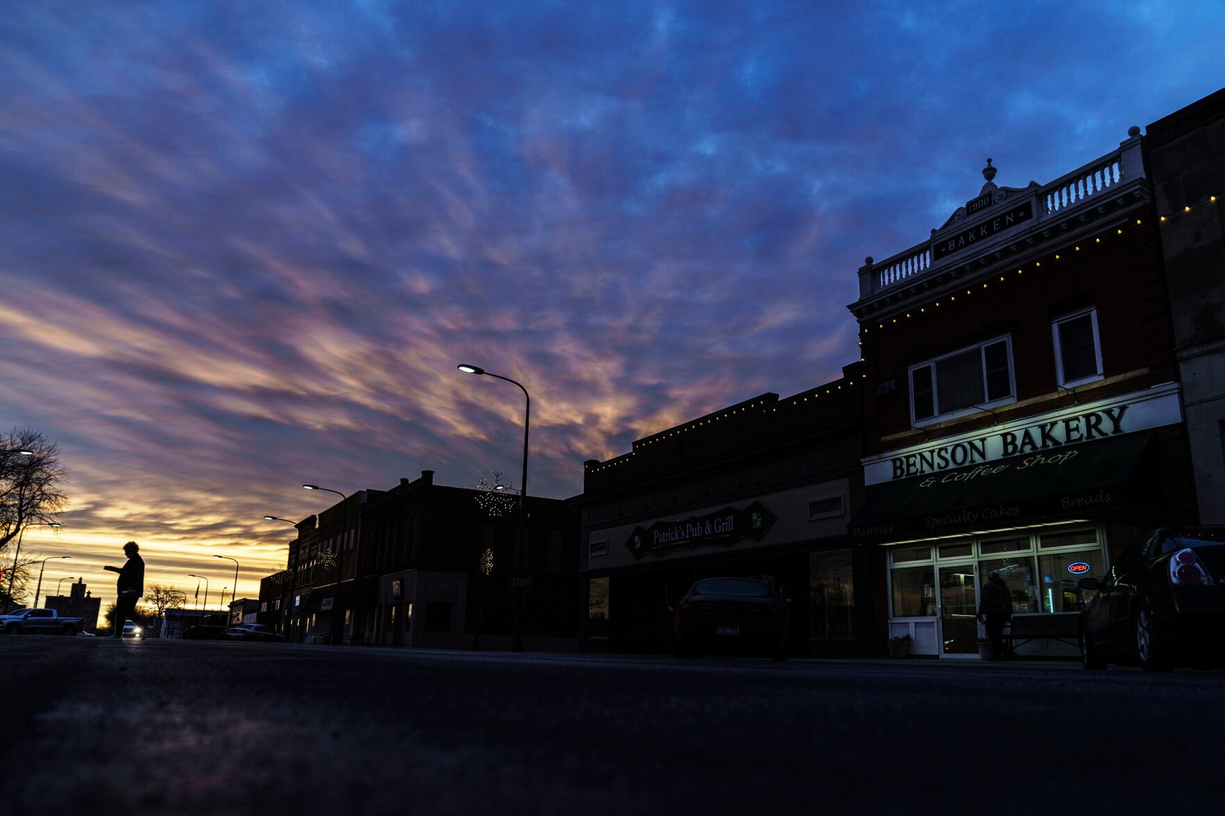 <p>A customer carries a box of baked goods from a bakery at sunrise in Benson, Minn., Wednesday, Dec. 1, 2021. One little town. Three thousand people. Two starkly different realities. It's another measure of how America's divisions don't just play out on cable television. It has seeped into the American fabric, all the way to Benson, where two neighbors, each in his own well-kept, century-old home, can live in different worlds. </p>