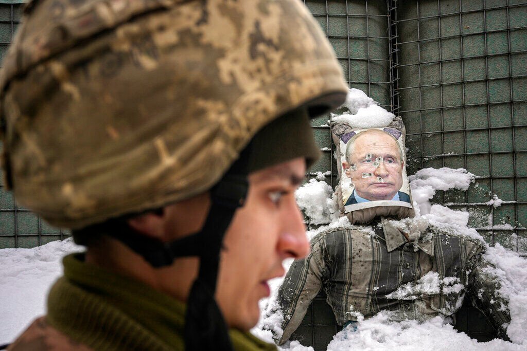 <p>FILE - A Ukrainian serviceman speaks, backdropped by a bullet riddled effigy of Russian President Vladimir Putin, during a media interview at a frontline position in the Luhansk region, eastern Ukraine, Tuesday, Feb. 1, 2022. </p>