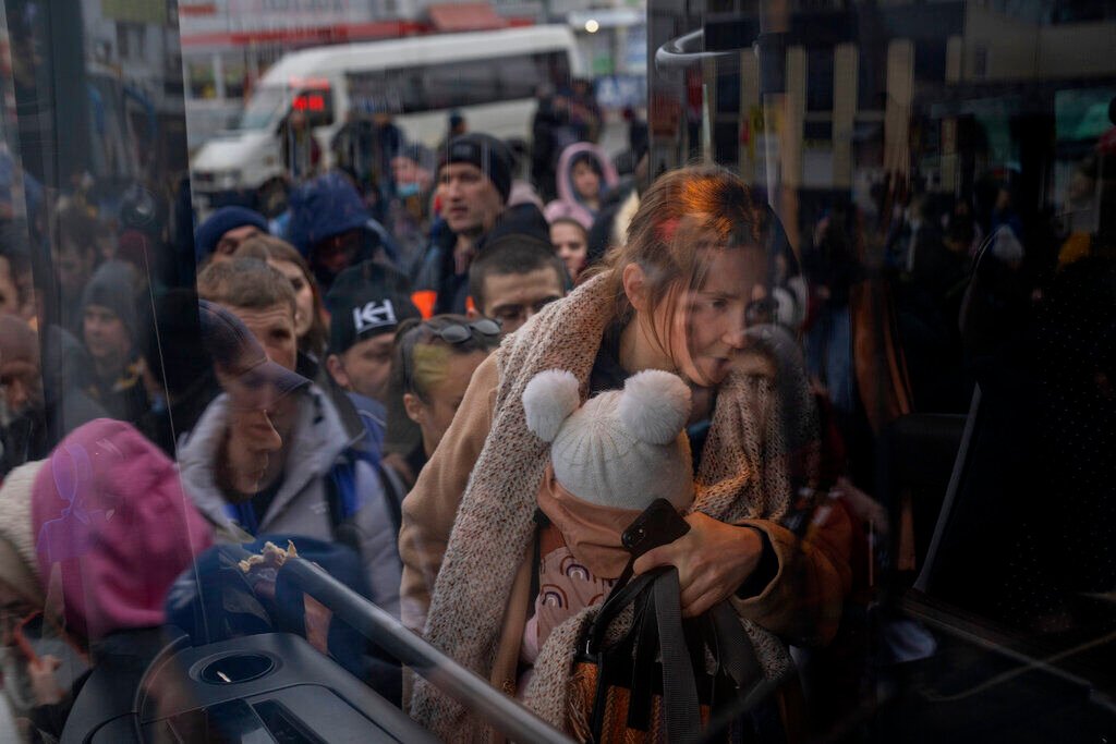 <p>A woman holds her baby as she gets on a bus leaving Kyiv, Ukraine, Feb. 24, 2022. </p>