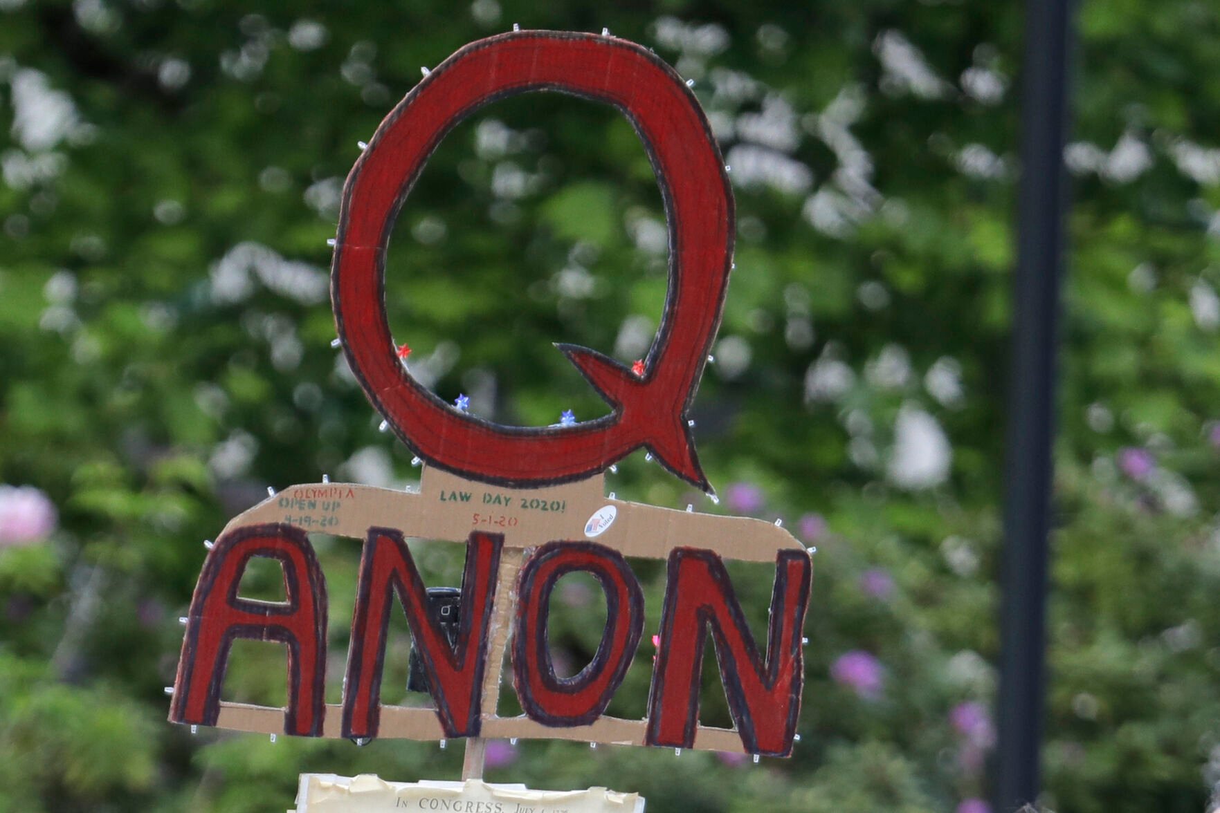 <p>A person carries a sign supporting QAnon during a protest rally in Olympia, Wash., on May 14, 2020. The QAnon conspiracy theory has been linked to acts of real-world violence, including last year's riot at the U.S. Capitol. In June 2021, a federal intelligence report warned that QAnon adherents could target Democrats and other political opponents for more violence. </p>