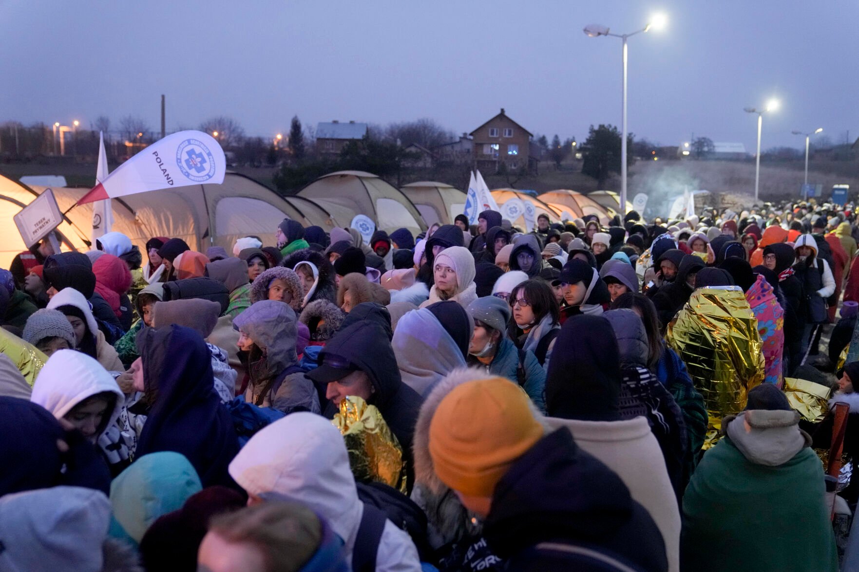 <p>Refugees wait in a crowd for transportation after fleeing from the Ukraine and arriving at the border crossing in Medyka, Poland, Monday, March 7, 2022. </p>