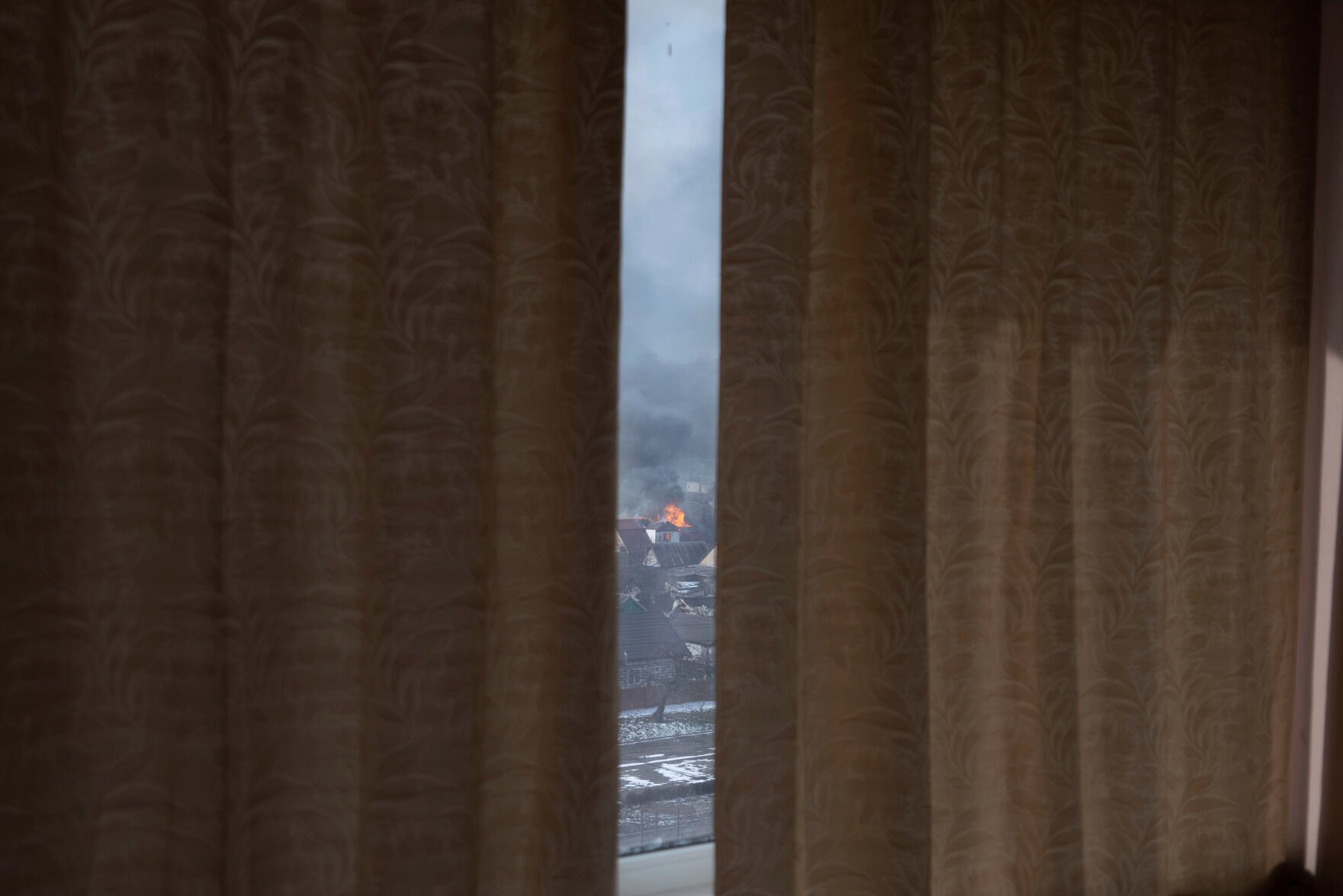 <p>Seen through partially drawn curtains a house burns after shelling in Mariupol, Ukraine, Saturday, March 12, 2022. </p>