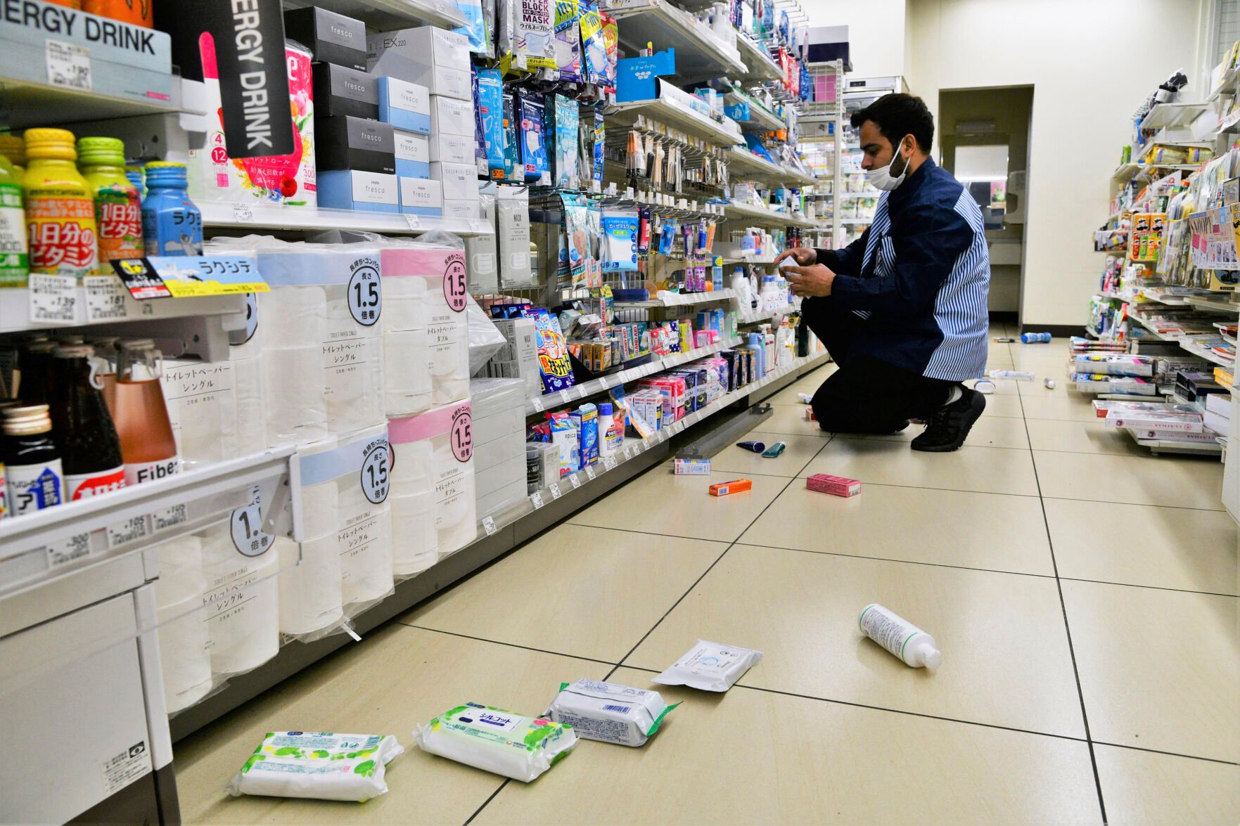 <p>An employee clears products, which fell from shells in a convenience store in Iwaki, Fukushima, folllowing the earthquake.</p>