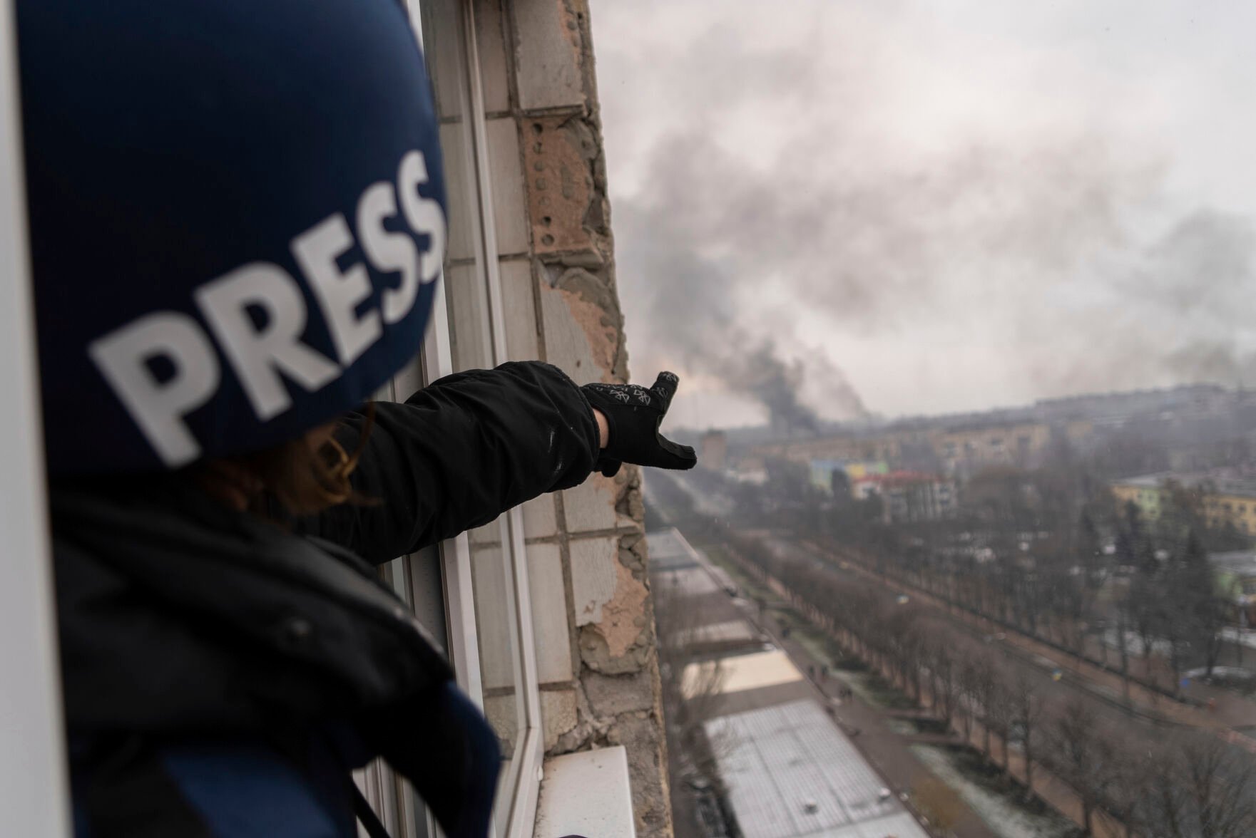 <p>Associated Press photographer Evgeniy Maloletka points at the smoke rising after an airstrike on a maternity hospital, in Mariupol, Ukraine, Wednesday, March 9, 2022. </p>