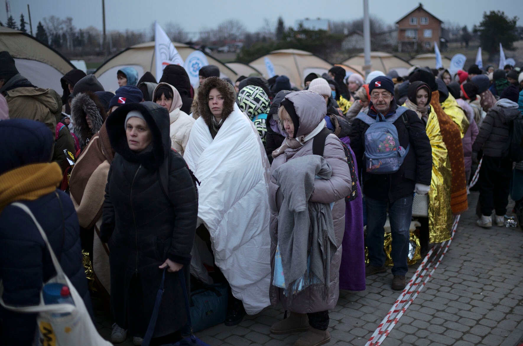 <p>Refugees wait in a crowd for transportation after fleeing from the Ukraine and arriving at the border crossing in Medyka, Poland, Monday, March 7, 2022. </p>