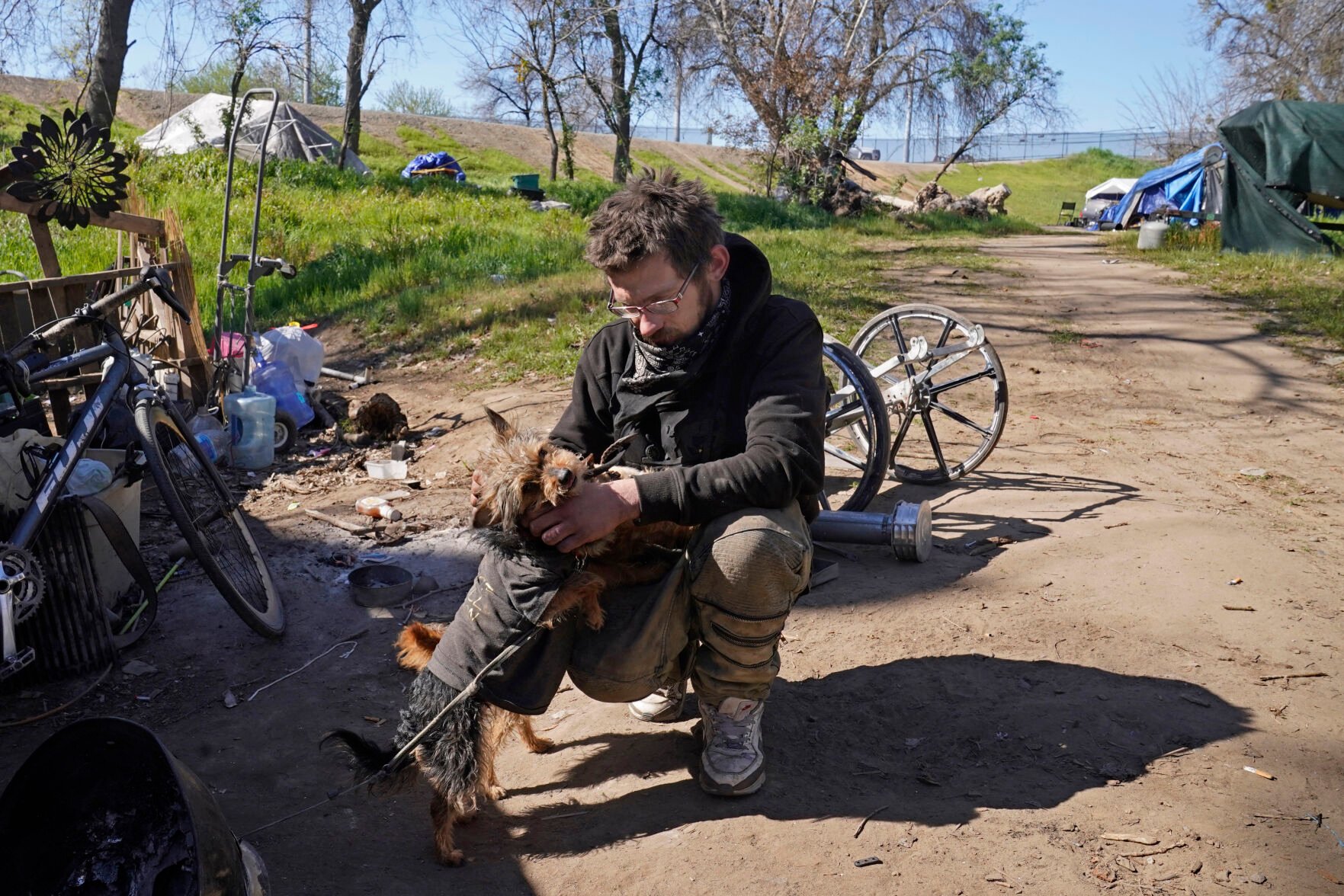 <p>Mark Bannister plays with his dog, Amelia, where he lives in a camp for people experiencing homelessness along the American River Parkway in Sacramento, Calif., on Feb. 24, 2022. Bannister said many people lacking housing do not want to go to shelters in Sacramento because pets are not allowed. </p>