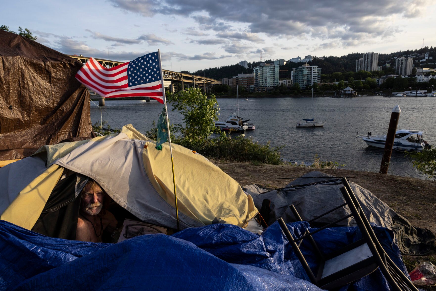 <p>FILE - Frank, who is experiencing homelessness, sits in his tent in Portland, Ore., next to the Willamette River on June 5, 2021. </p>