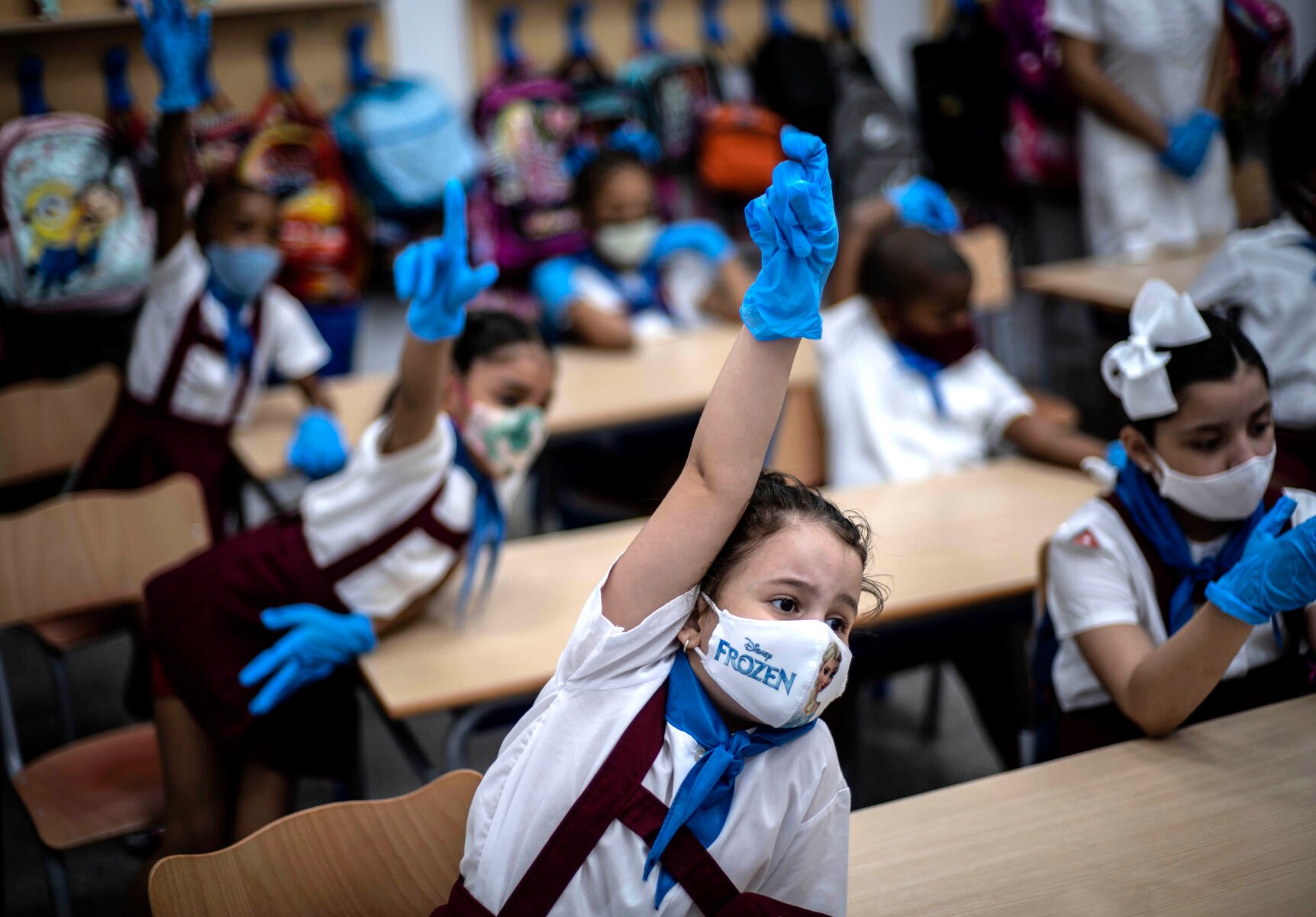 <p>Wearing masks and plastic gloves amid the spread of the coronavirus, girls raise her hands during class in Havana, Cuba, Monday, Nov. 2, 2020. </p>