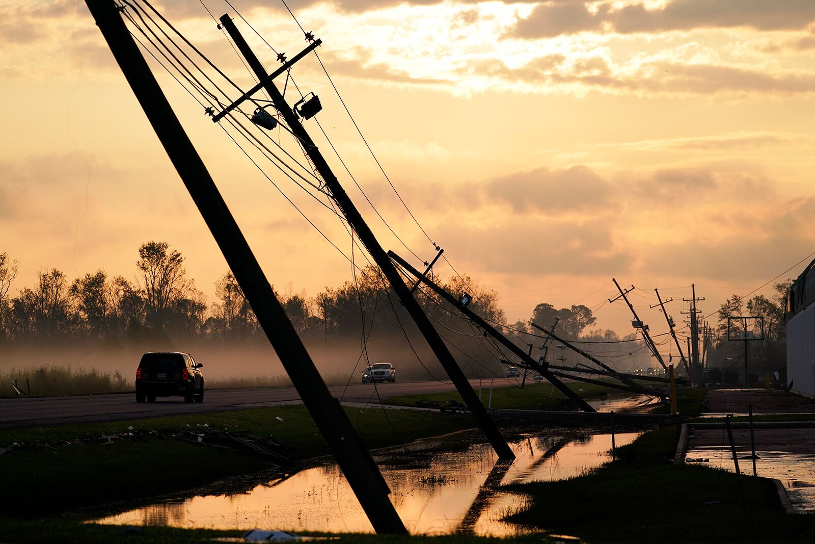 <p>Downed power lines slump over a road in the aftermath of Hurricane Ida in Louisiana in 2021.</p>