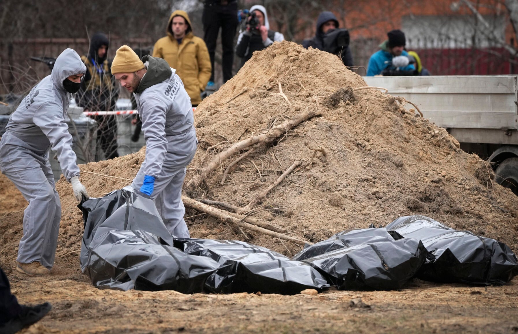<p>Men wearing protective gear exhume the bodies of civilians killed during the Russian occupation in Bucha, in the outskirts of Kyiv, Ukraine, Wednesday, April 13, 2022. Dozens of bodies of civilians executed by the Russian troops have been exhumed already from the mass grave. (AP Photo/Efrem Lukatsky)</p>