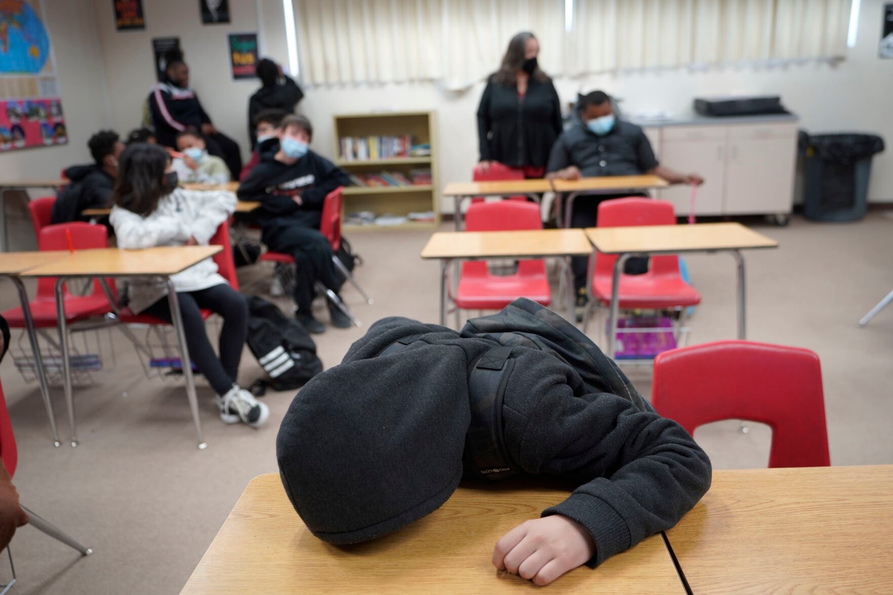 <p>An unidentified student rests on his desk as the Mojave Unified School District Superintendent Katherine Aguirre, center rear, addresses students before their spring break at California City Middle School in California City, Calif., on Friday, March 11, 2022. </p>