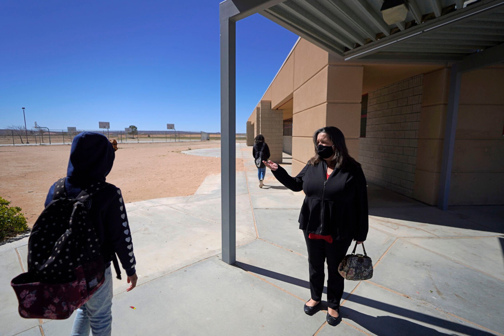 <p>Mojave Unified School District Superintendent Katherine Aguirre, right, greets students before the spring break at the California City Middle School in California City, Calif., on Friday, March 11, 2022. </p>