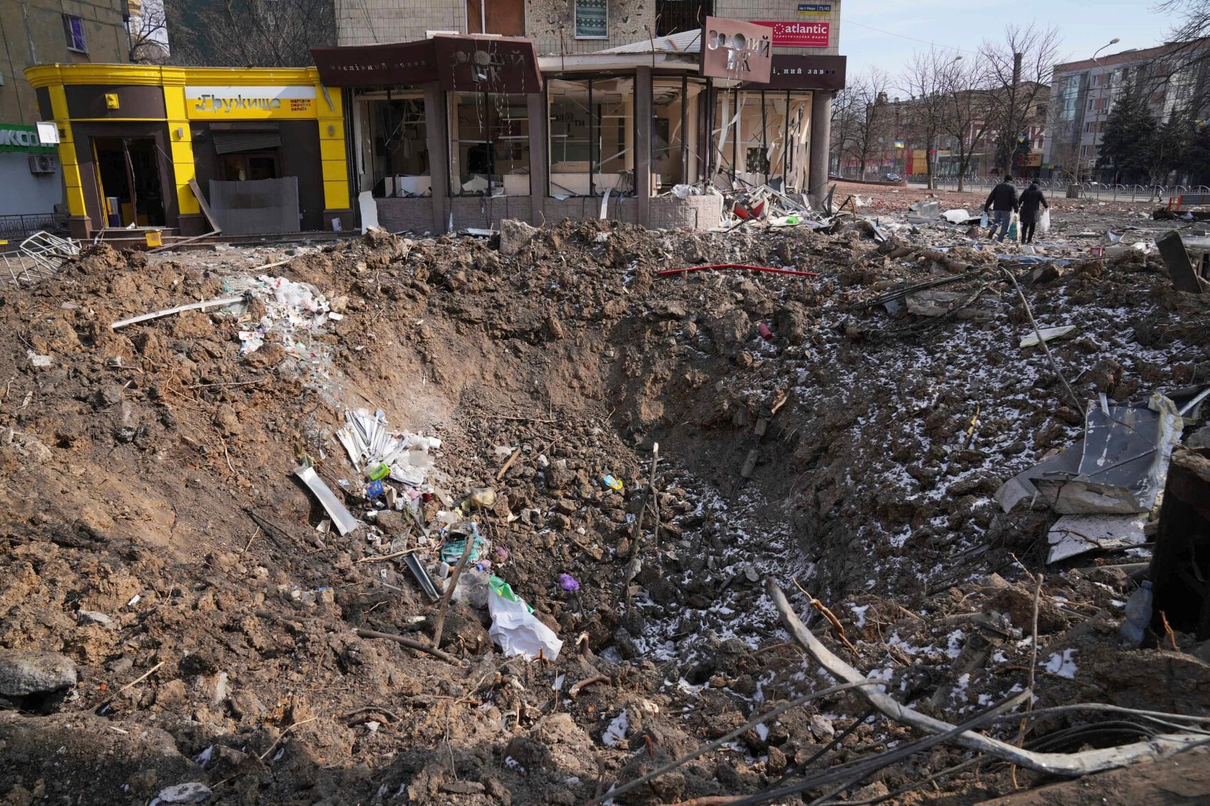 <p>FILE - People walk past a crater from the explosion in Mira Avenue (Avenue of Peace) in Mariupol, Ukraine, March 13, 2022. Russia is bracing up for a massive new offensive in eastern Ukraine, hoping to reverse its fortunes on the battlefield after a catastrophic start of the invasion.</p>