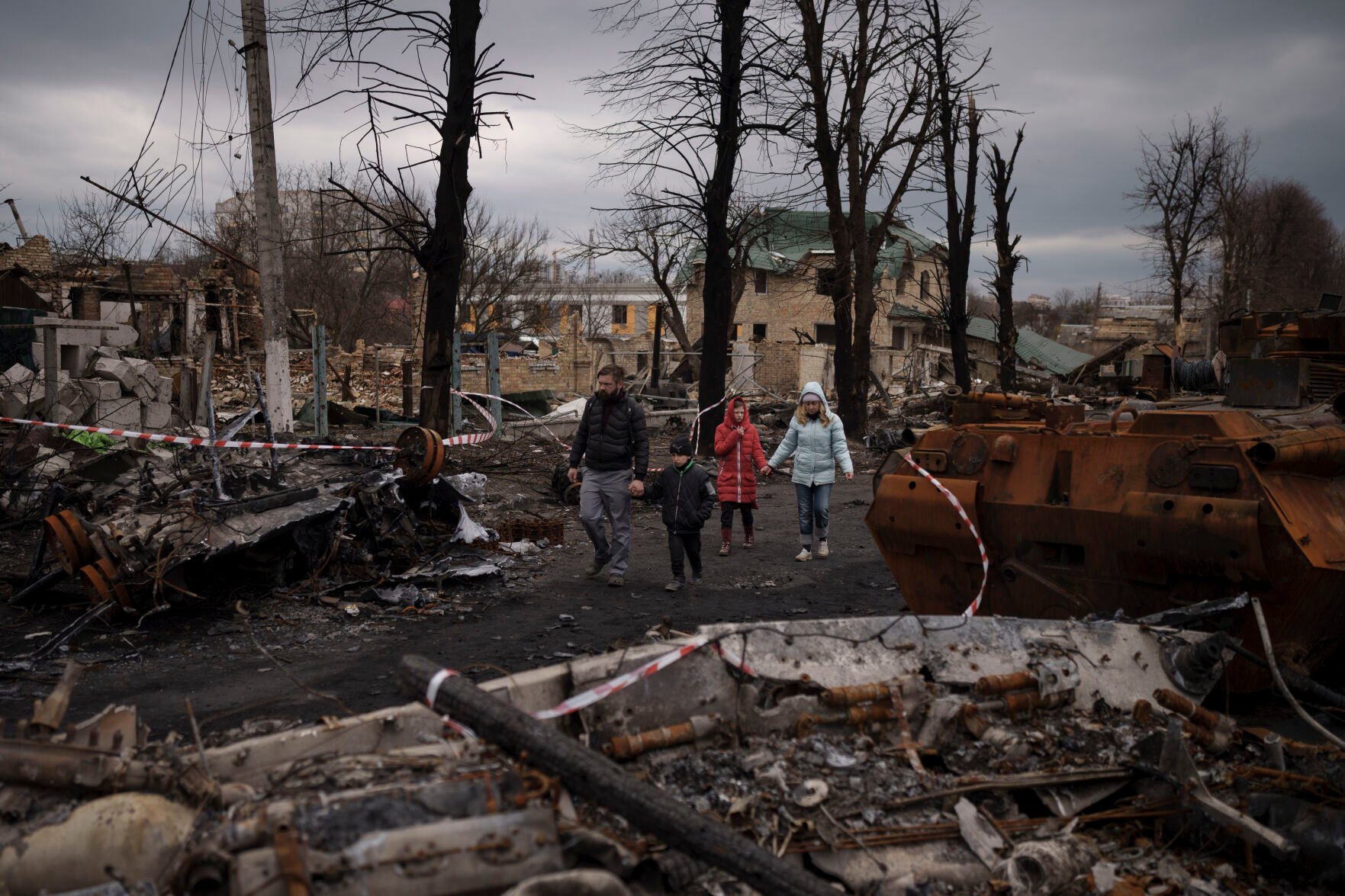 <p>FILE - A family walks amid destroyed Russian tanks in Bucha, on the outskirts of Kyiv, Ukraine, Wednesday, April 6, 2022. (AP Photo/Felipe Dana, File)</p>