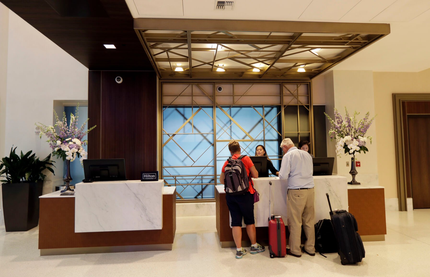 <p>FILE- In this Sept. 5, 2018, file photo guests stand at the front desk at the Embassy Suites by Hilton hotel in Seattle's Pioneer Square neighborhood in Seattle. Many major hotel chains are embracing all-inclusive offerings. For example, Hyatt recently announced an integration with AMR Collection brands, a group of about 100 all-inclusive resorts. Others, including Walt Disney World Resort, are workshopping the all-inclusive model, offering more specialized entertainment or outdoor access. These vacation packages are attractive to travelers in 2022, as paying for the bulk of travel expenses at once makes it easier to budget. For others, the opulence coupled with the minimal headache of planning every component of a trip is worth the higher price tag. (AP Photo/Ted S. Warren, File)</p>