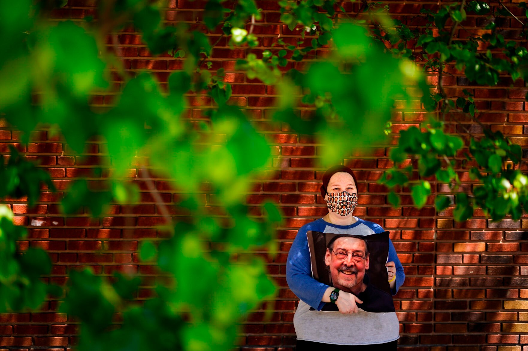 <p>Sara Atkins poses for a photo, in Wynnewood, Pa., Tuesday, May 10, 2022, while holding a pillow with an image of her father Andy Rotman-Zaid, who died of COVID-19 in December 2020. She channels her grief into fighting for global vaccination and better access to health care to honor her father. </p>