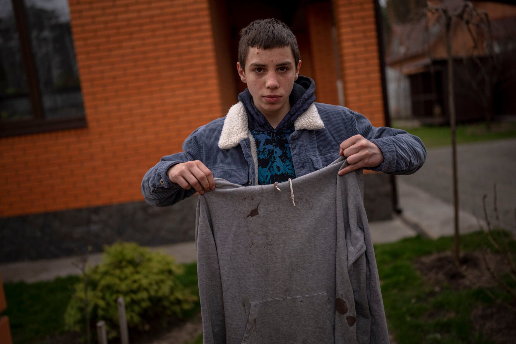 <p>Yura Nechyporenko, 15, holds the hoodie he was wearing the day a Russian soldier tried to kill him in Bucha, on the outskirts of Kyiv, Ukraine, on Tuesday, April 19, 2022. </p>