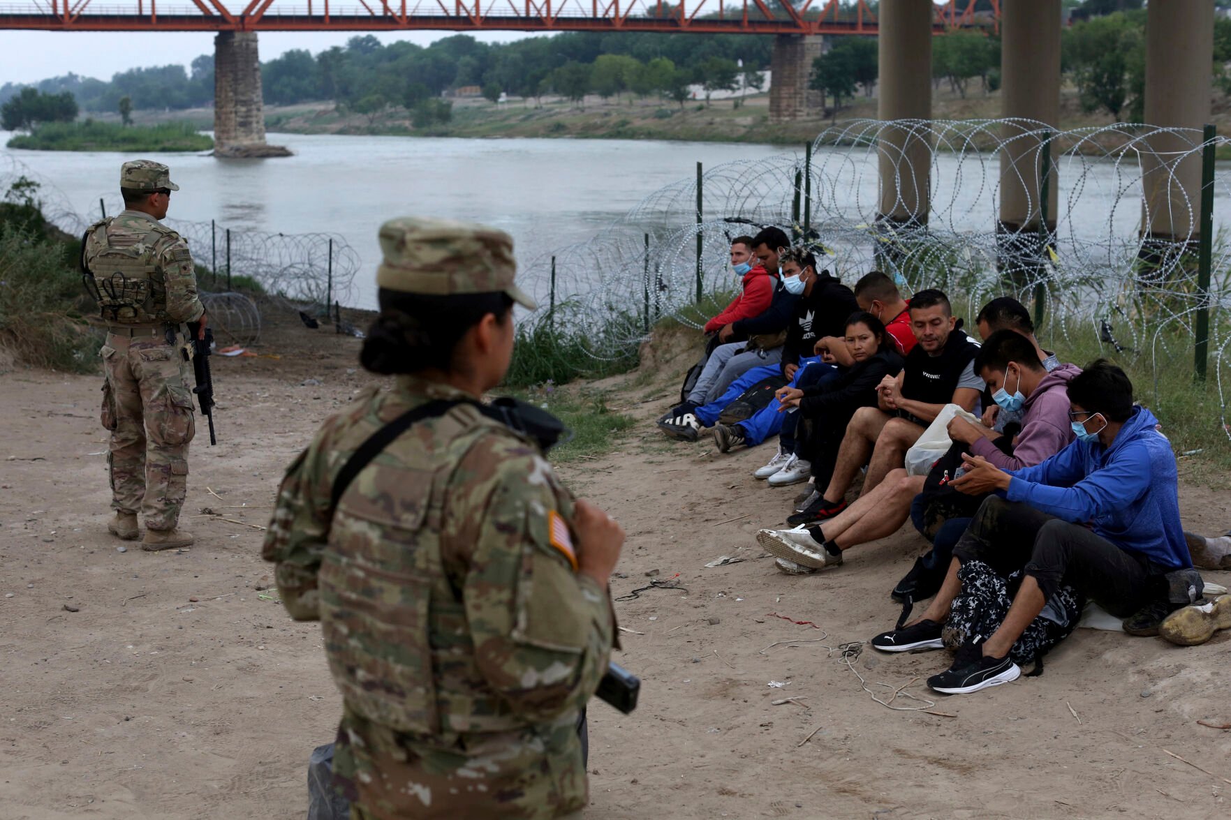 <p>Migrants who had crossed the Rio Grande river into the U.S. are under custody of National Guard members as they await the arrival of U.S. Border Patrol agents in Eagle Pass, Texas, Friday, May 20, 2022. The Eagle Pass area has become increasingly a popular crossing corridor for migrants, especially those from outside Mexico and Central America, under Title 42 authority, which expels migrants without a chance to seek asylum on grounds of preventing the spread of COVID-19. A judge was expected to rule on a bid by Louisiana and 23 other states to keep Title 42 in effect before the Biden administration was to end it Monday. (AP Photo/Dario Lopez-Mills)</p>
