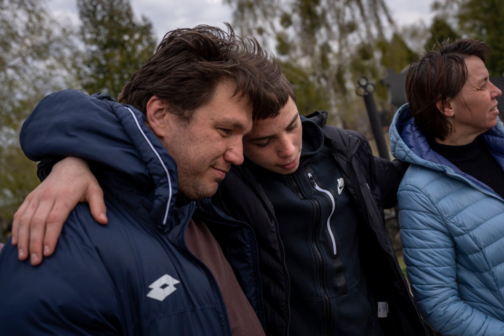 <p>Yura Nechyporenko, 15, hugs his uncle Andriy Nechyporenko next to the grave of his father Ruslan Nechyporenko at the cemetery in Bucha, on the outskirts of Kyiv, Ukraine, on Monday, April 25, 2022. </p>