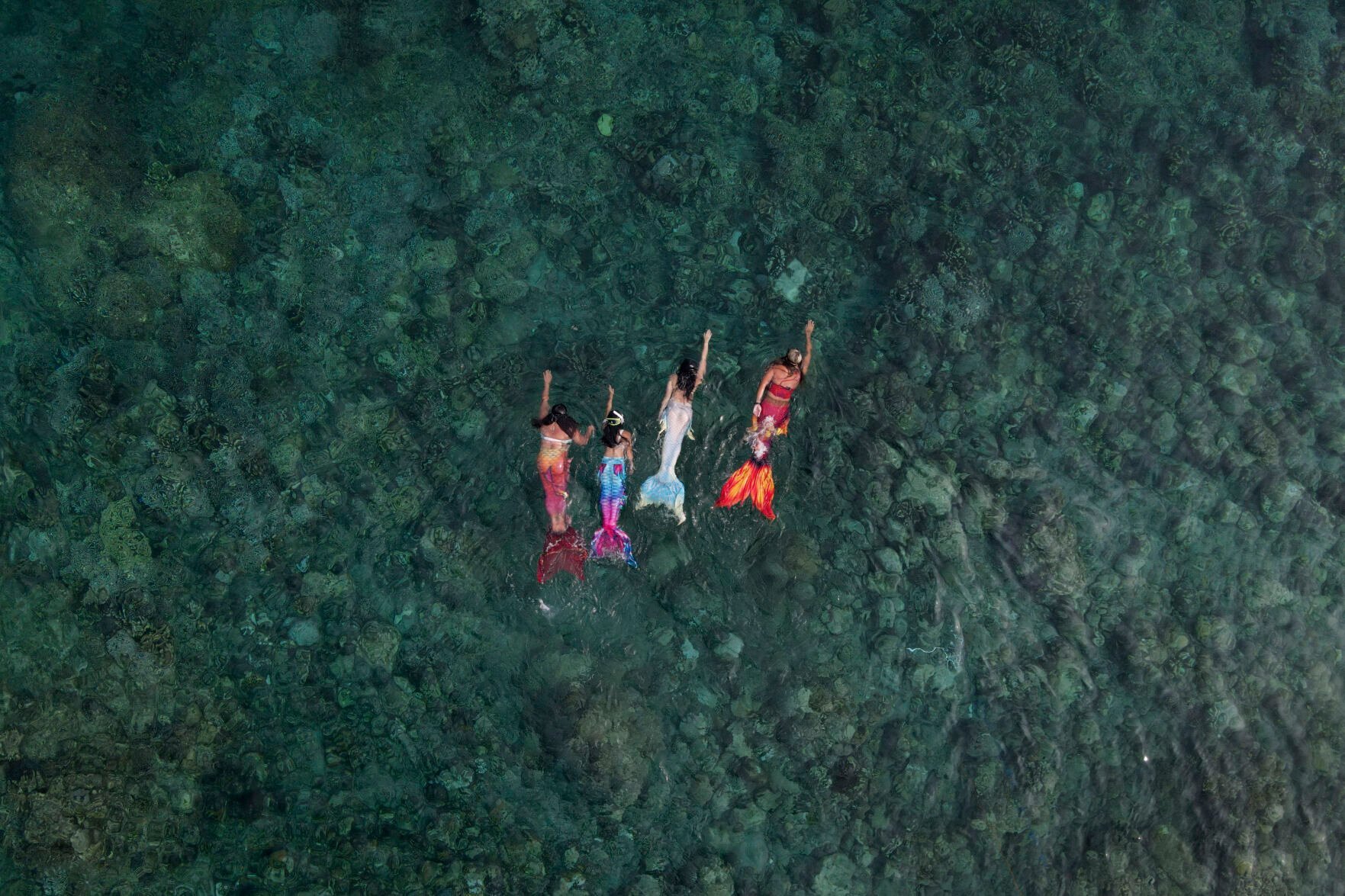 <p>Queen Pangke Tabora, right, swims with her students, from left, Shelah Candado, Jennica Secuya and Meryll Louise Reque, during a mermaiding class in Mabini, Batangas province, Philippines on Sunday, May 22, 2022. </p>