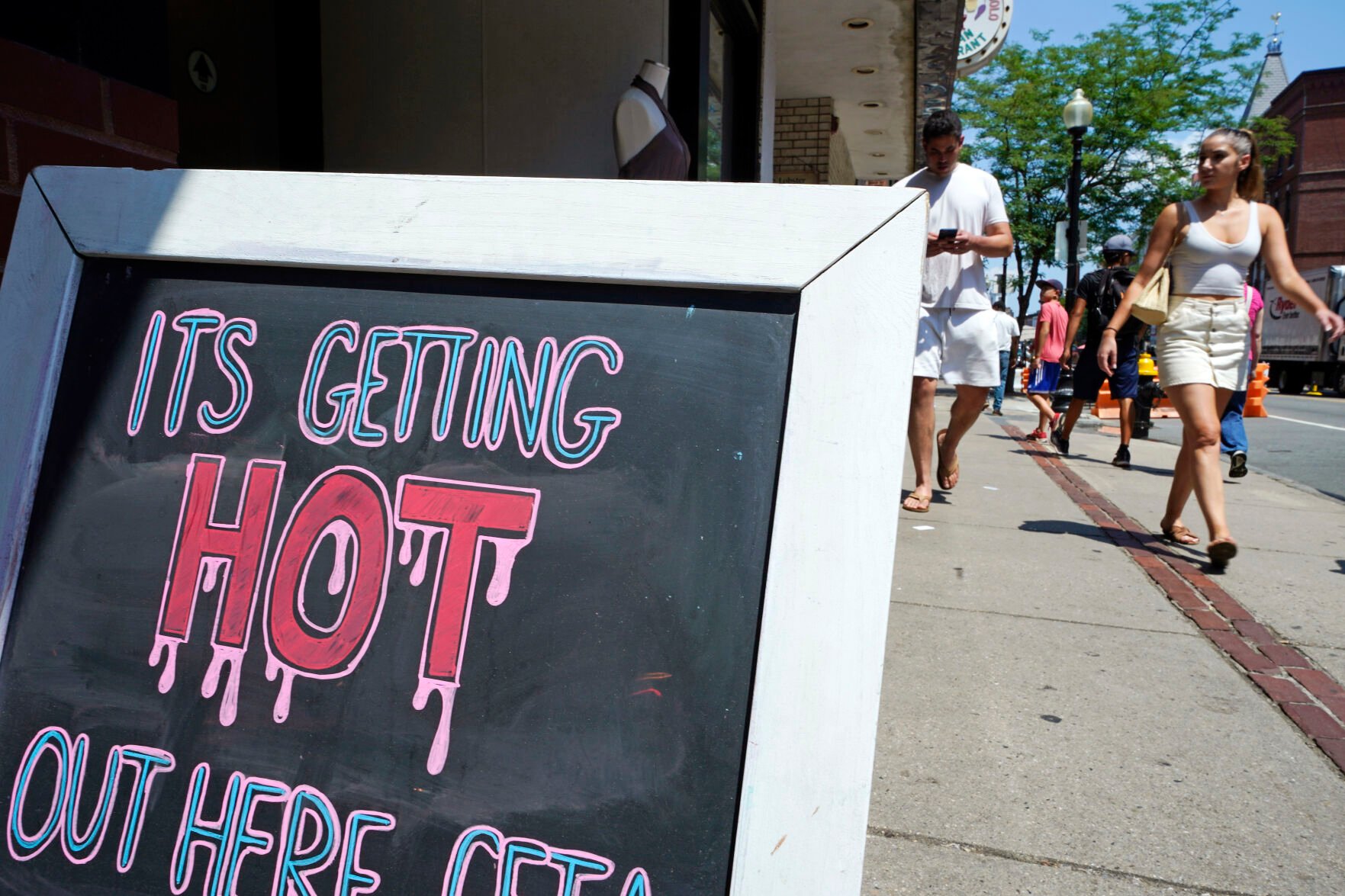 <p>With temperatures hovering in the mid-90s, people walk near a sign during a summer heat wave July 21, 2022, in Boston.</p>