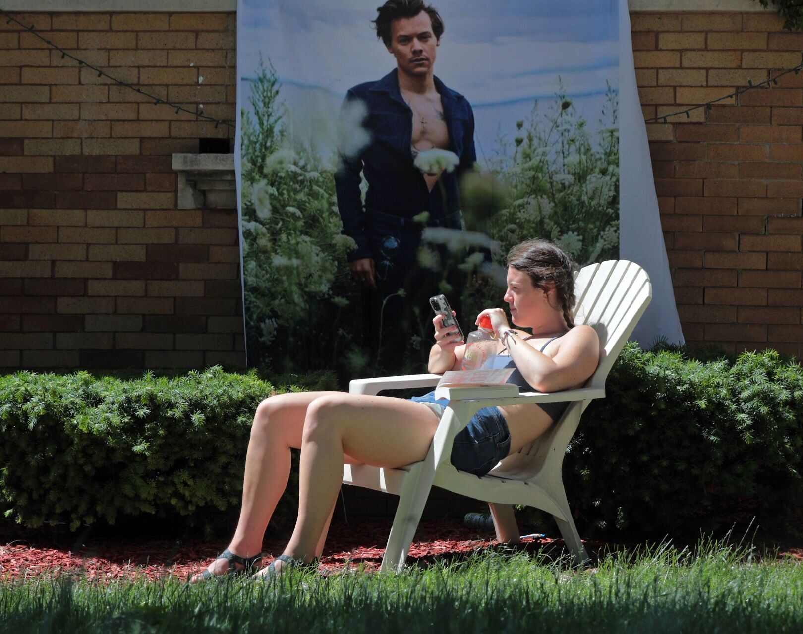 <p>Gretchen Bushman, a fan of singer Harry Styles, seeks relief from the heat outside her unairconditioned apartment in Madison, Wis., on June 14 when the high reached 96 degrees.</p>