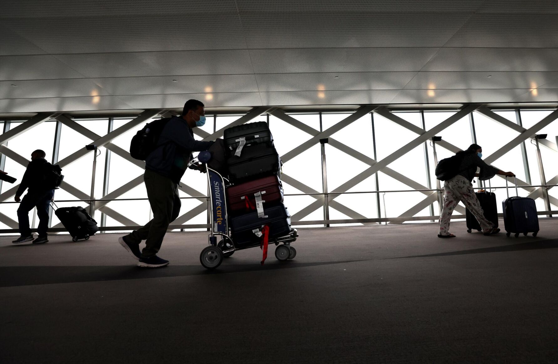 <p>Travelers walk with their luggage at San Francisco International Airport on July 1. Fewer people are expected to be flying this fall compared with this past summer. And Labor Day weekend airfares are down.</p>