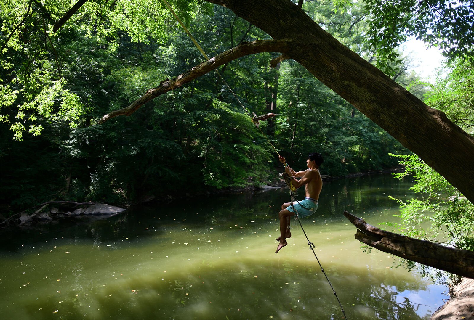 <p>A teenager leaps toward water on a rope swing at a park in Philadelphia during a heat wave on Aug. 4, 2022.</p>