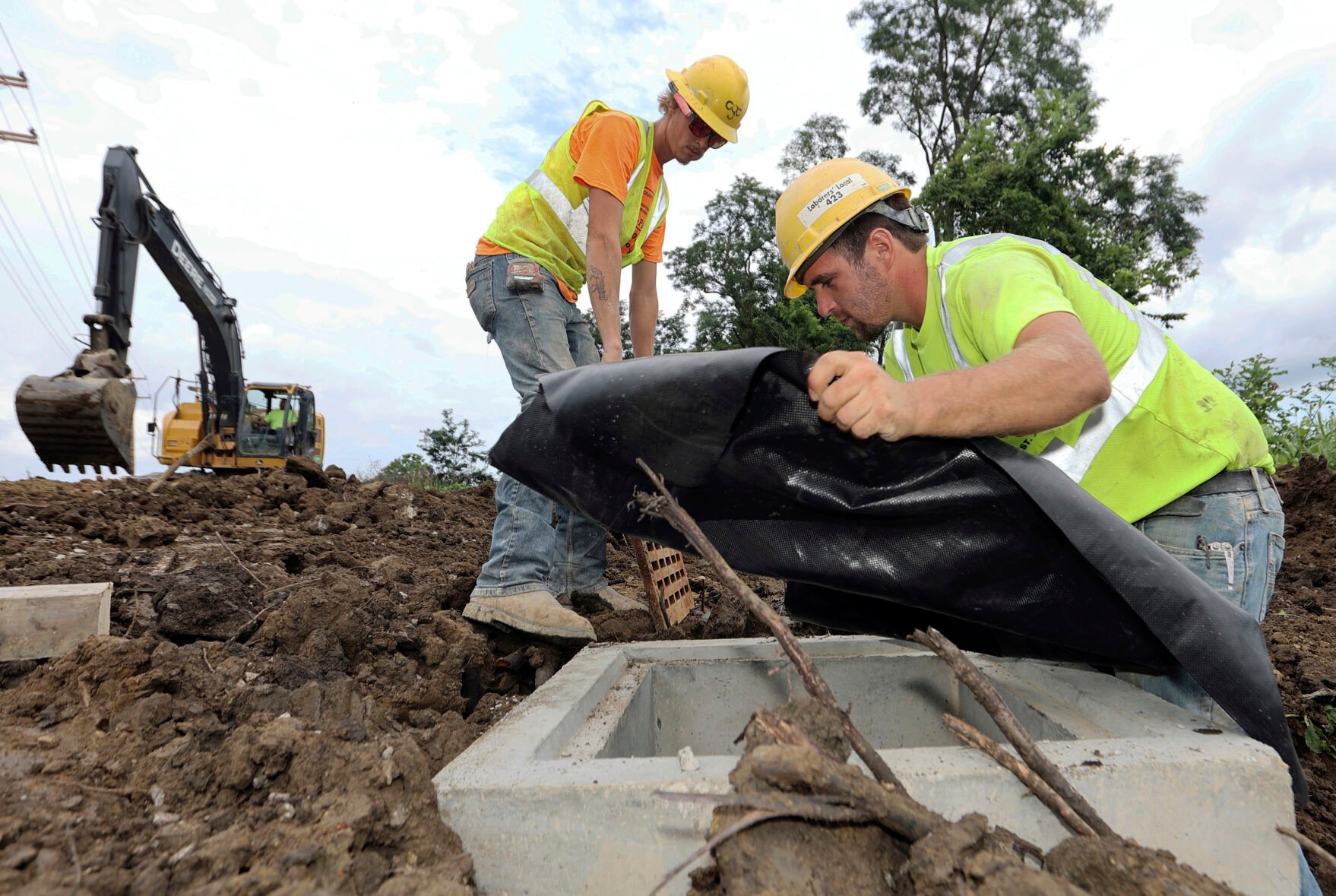<p>Taylor Purdy, right, a pipe layer with Complete General Construction, and colleague Adam Clary install temporary silt protection for a catch basin near the new Intel semiconductor manufacturing plant construction site in Johnstown, Ohio, Friday, Aug. 5, 2022. </p>