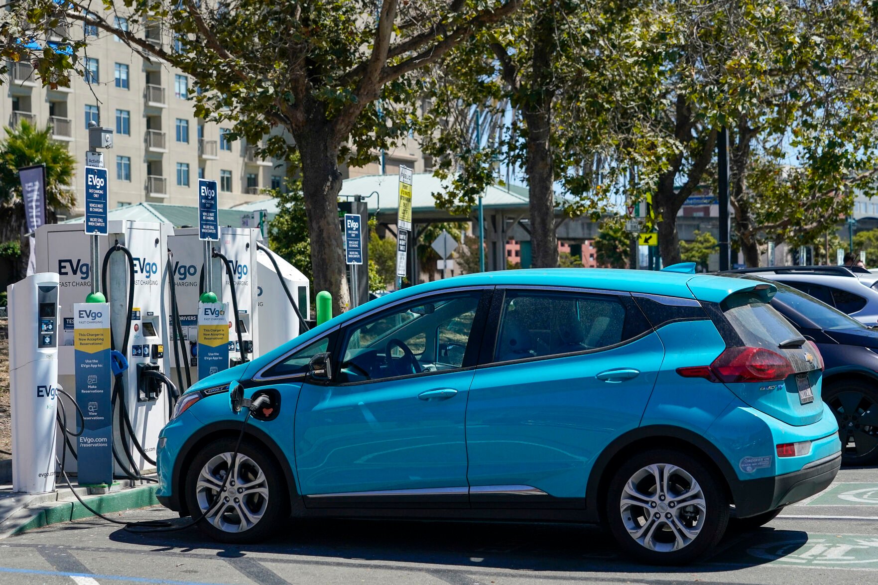 <p>FILE - Electric vehicles can be seen charging at a shopping center in Emeryville, Calif., on Aug. 10, 2022. </p>
