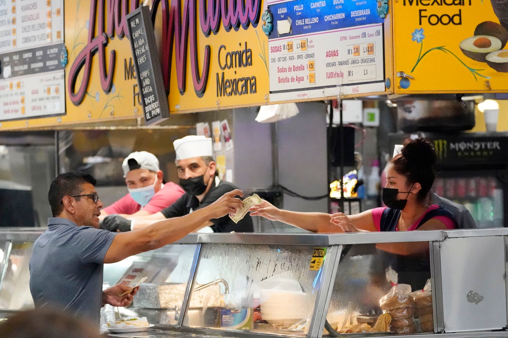 <p>Money is exchanged at a food stand while workers wear face masks inside Grand Central Market on Wednesday, July 13, 2022, in Los Angeles. Falling gas prices gave Americans a slight break from the pain of high inflation last month, though the surge in overall prices slowed only modestly from the four-decade high it reached in June. And even as gas prices fall, inflation in services such as health care, rents and restaurant meals is accelerating.</p>