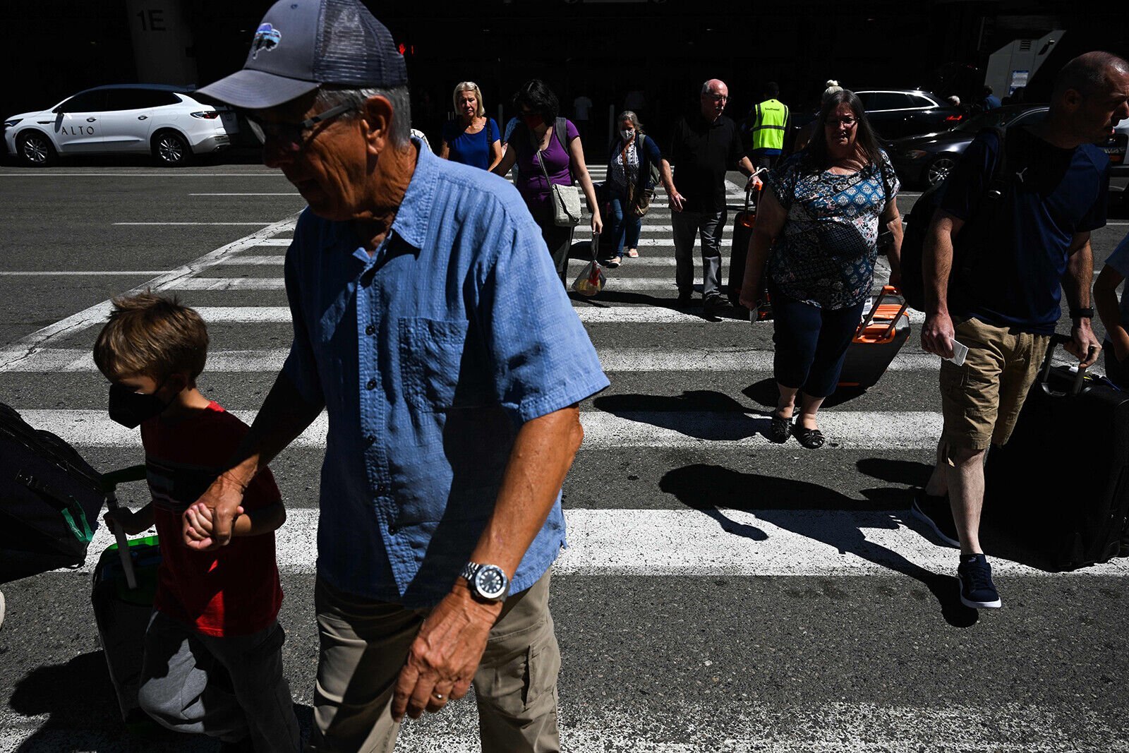 <p>Passengers carry baggage across a street to a parking garage at Los Angeles International Airport on August 10. While no one knows for certain what lies ahead for flight disruptions, airfares are definitely down.</p>