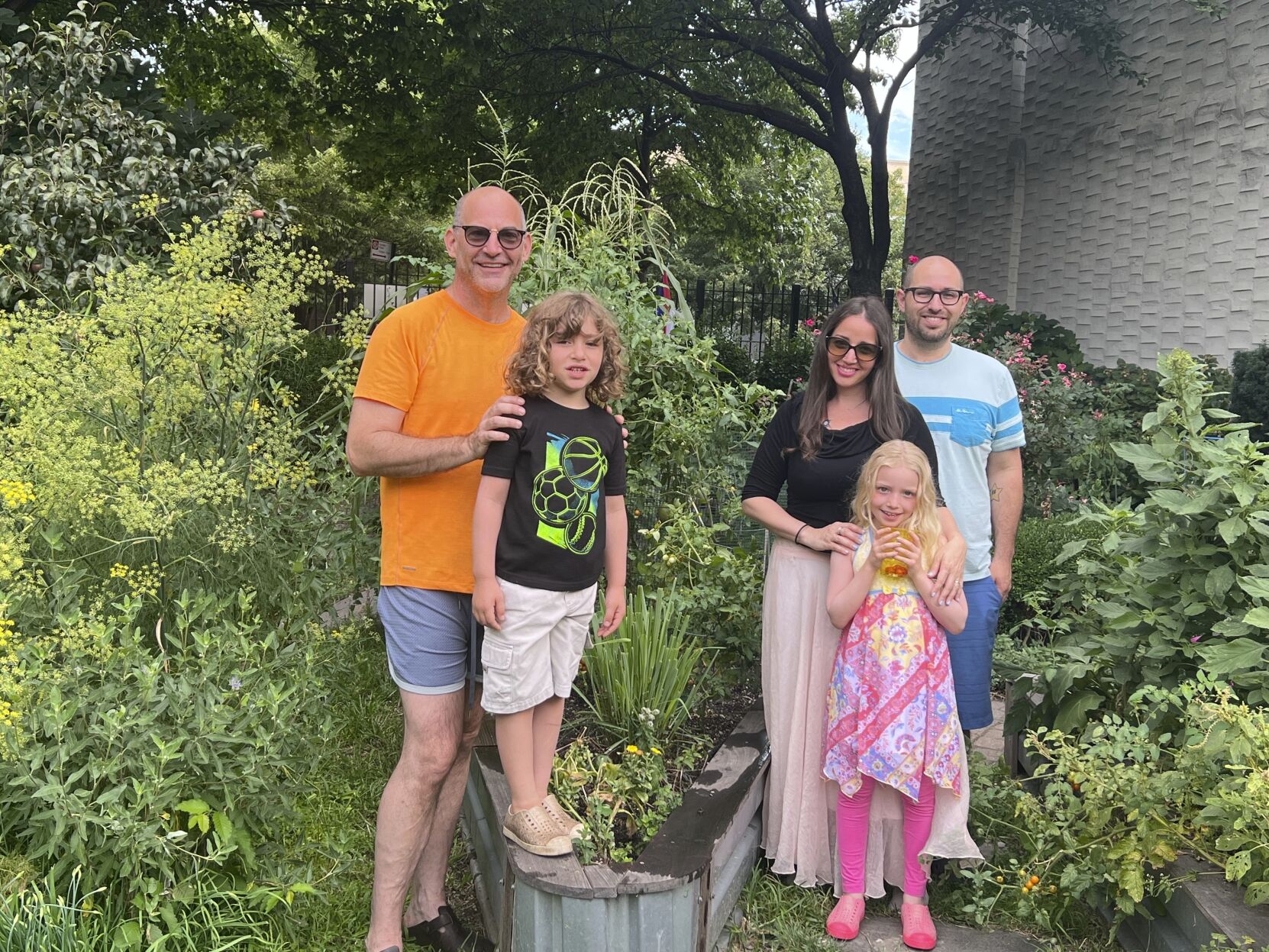 <p>This Aug. 12, 2022, photo shows, from left, Garden sitter Jono Waks, left, with Lev Guttenberg, from second left, Tal Guttenberg, Zoe Guttenberg and Doug Guttenberg at the Scholes Street Children’s Garden in the Brooklyn borough of New York. The Guttenberg family leaves the care of their community plot and backyard garden to their neighbor, Waks, when they spend a month at their Detroit home each summer. (Jono Waks via AP).</p>