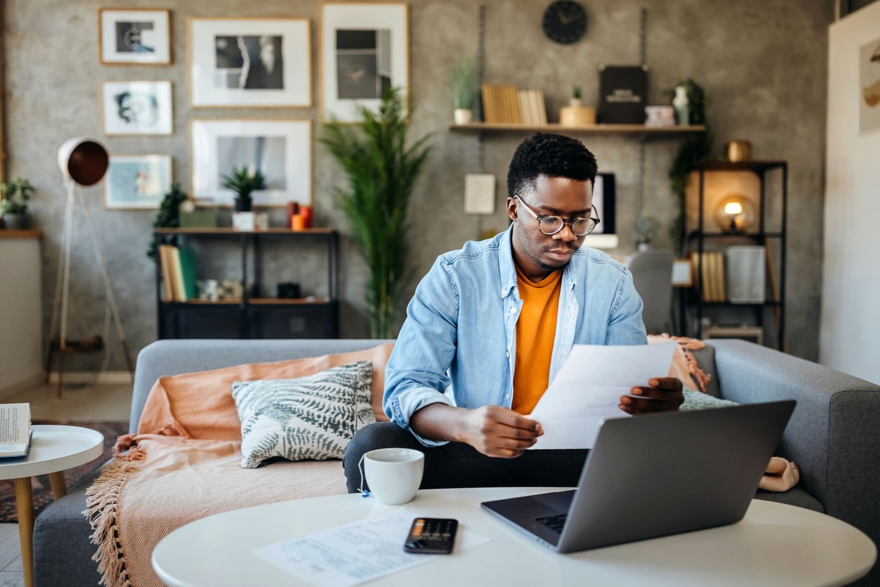 <p>Shot of a young man going over his finances at home</p>