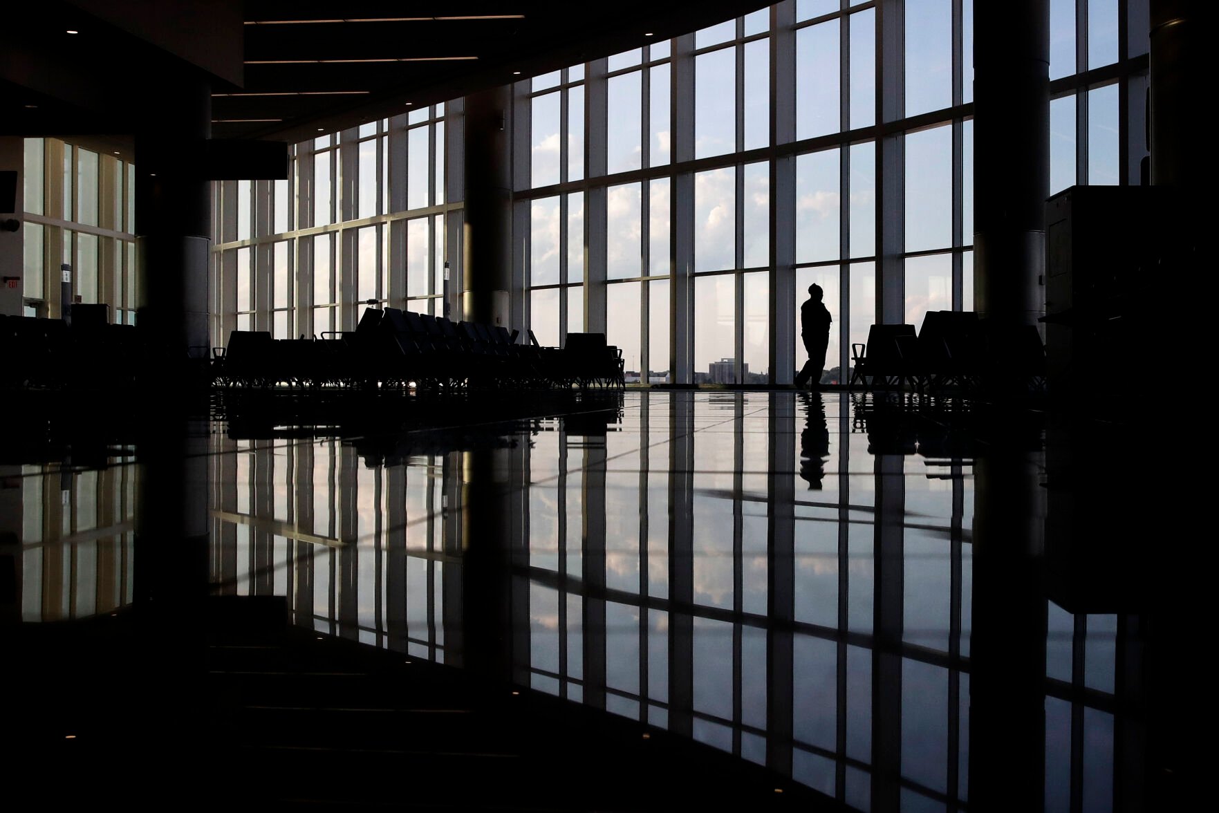 <p>In this June 1, 2020, photo, a woman looks through a window at a near-empty terminal at an airport in Atlanta.</p>