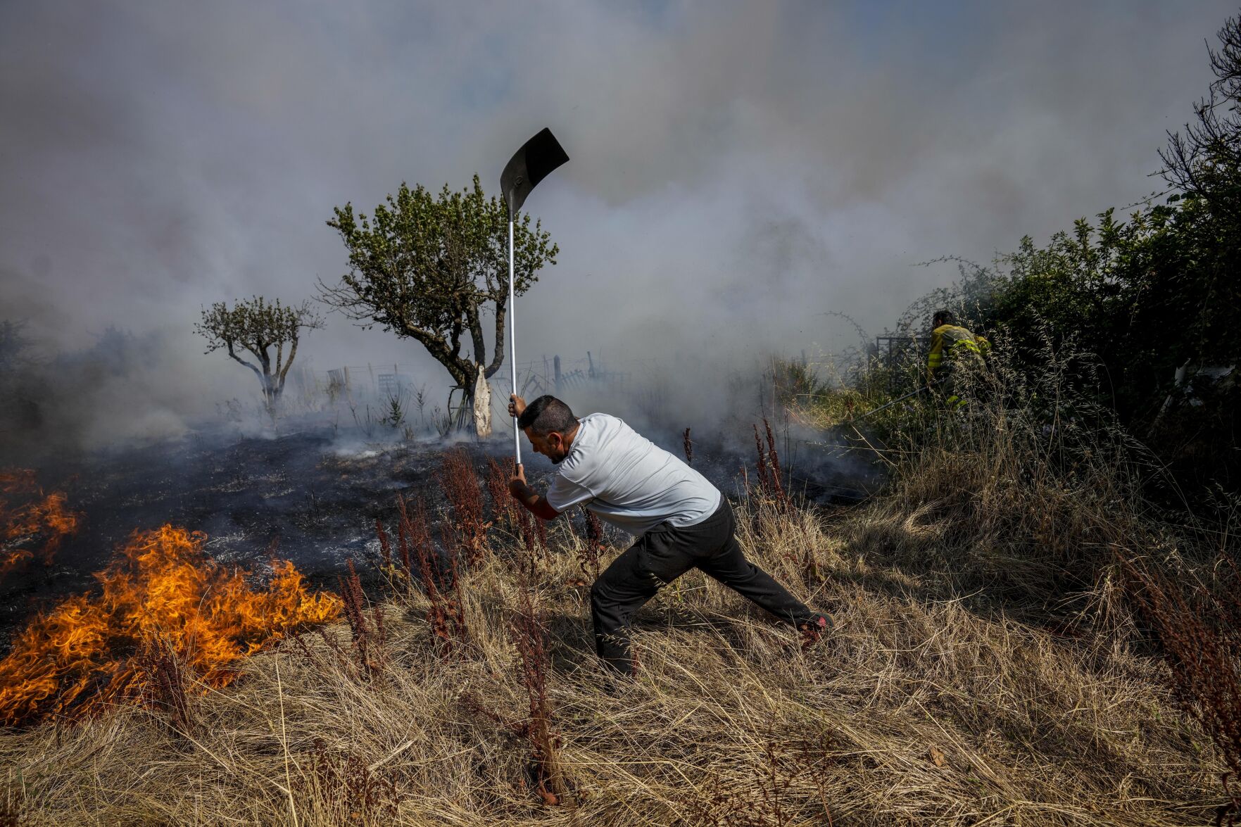 <p>A local resident fights a forest fire with a shovel during a wildfire in Tabara, north-west Spain, Tuesday, July 19, 2022. Firefighters battled wildfires raging out of control in Spain and France as Europe wilted under an unusually extreme heat wave that authorities in Madrid blamed for hundreds of deaths. (AP Photo/Bernat Armangue)</p>