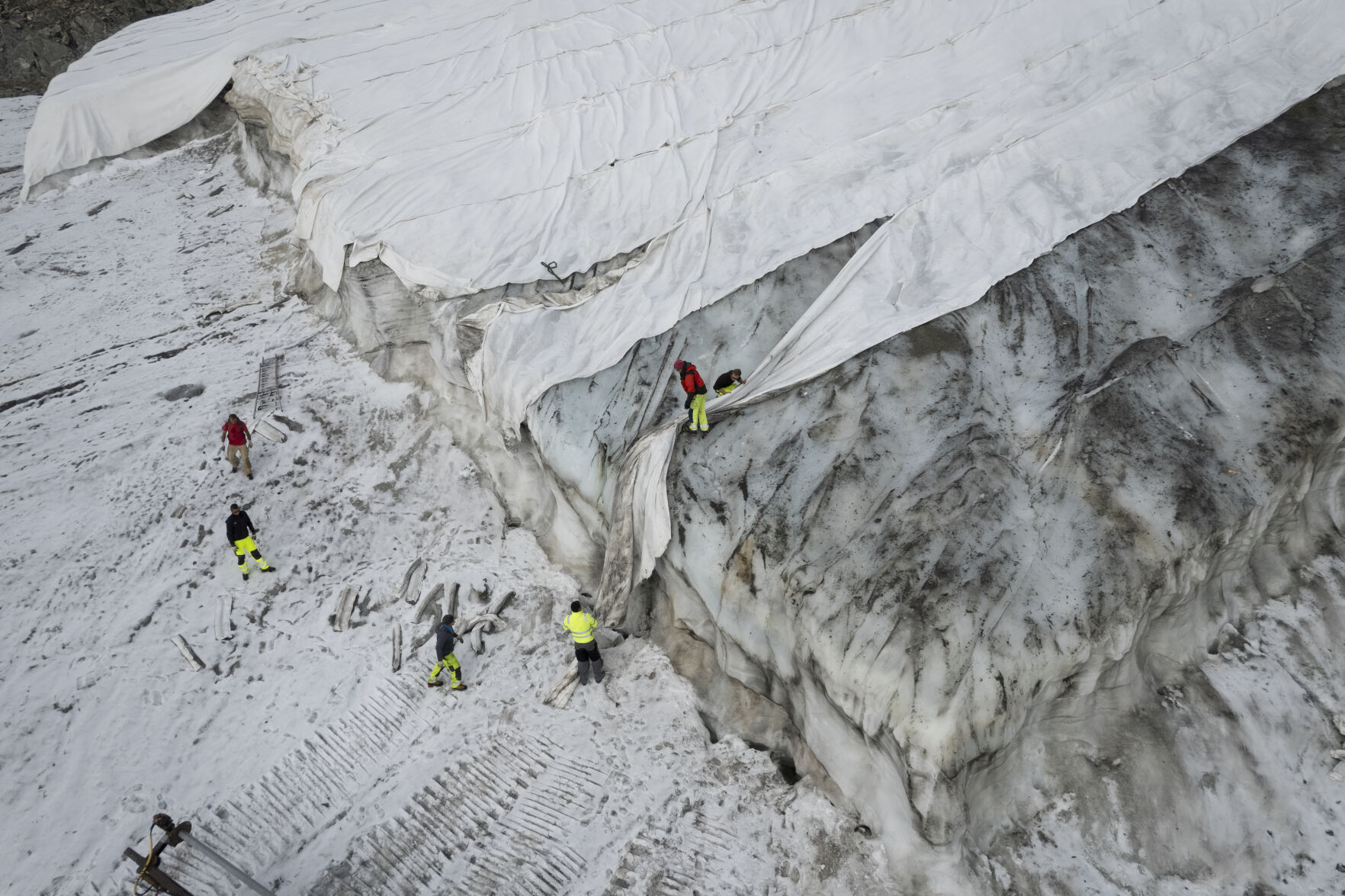 <p>FILE --People work on a tarpaulin which cover the ice of the Corvatsch glacier, near Samedan, Switzerland, Monday, Sept. 5, 2022. Glaciologists have stopped their program to measure the glacier. The decision has already been taken in 2019 and the hot summer of 2022 has led to "extreme losses of ice" and the end of the program. The covered part of the glacier is used as a ski slope in winter. (Gian Ehrenzeller/Keystone via AP,file)</p>