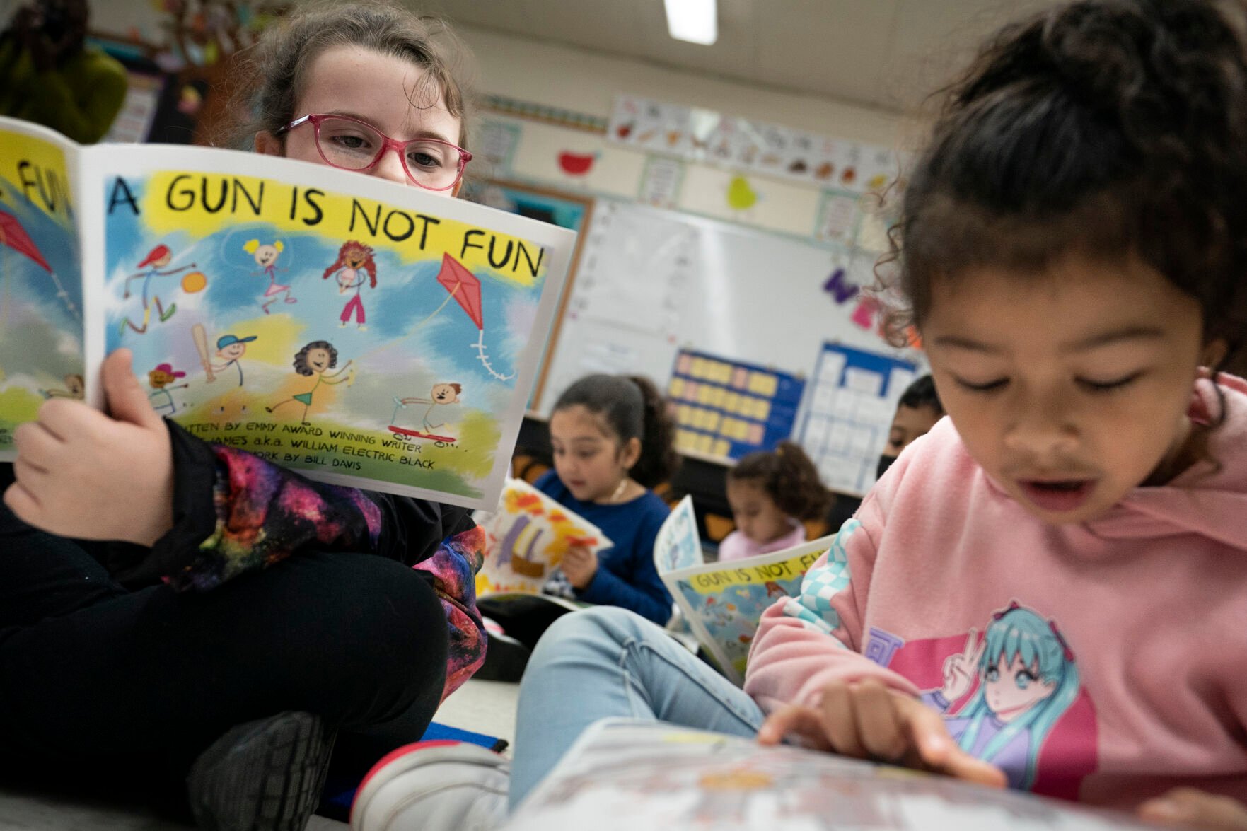 <p>Children read as Ian Ellis James, an Emmy award-winning Sesame Street writer known by his stage name William Electric Black, leads a first grade class in a book reading on urban gun violence prevention at the Drexel Avenue School, Monday, Oct. 3, 2022, in Westbury, N.Y. </p>